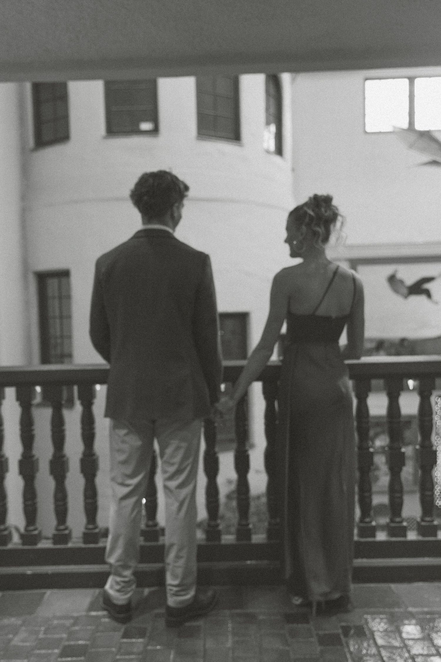 People stand silhouetted against a railing in a black and white photograph showing multiple similar poses.