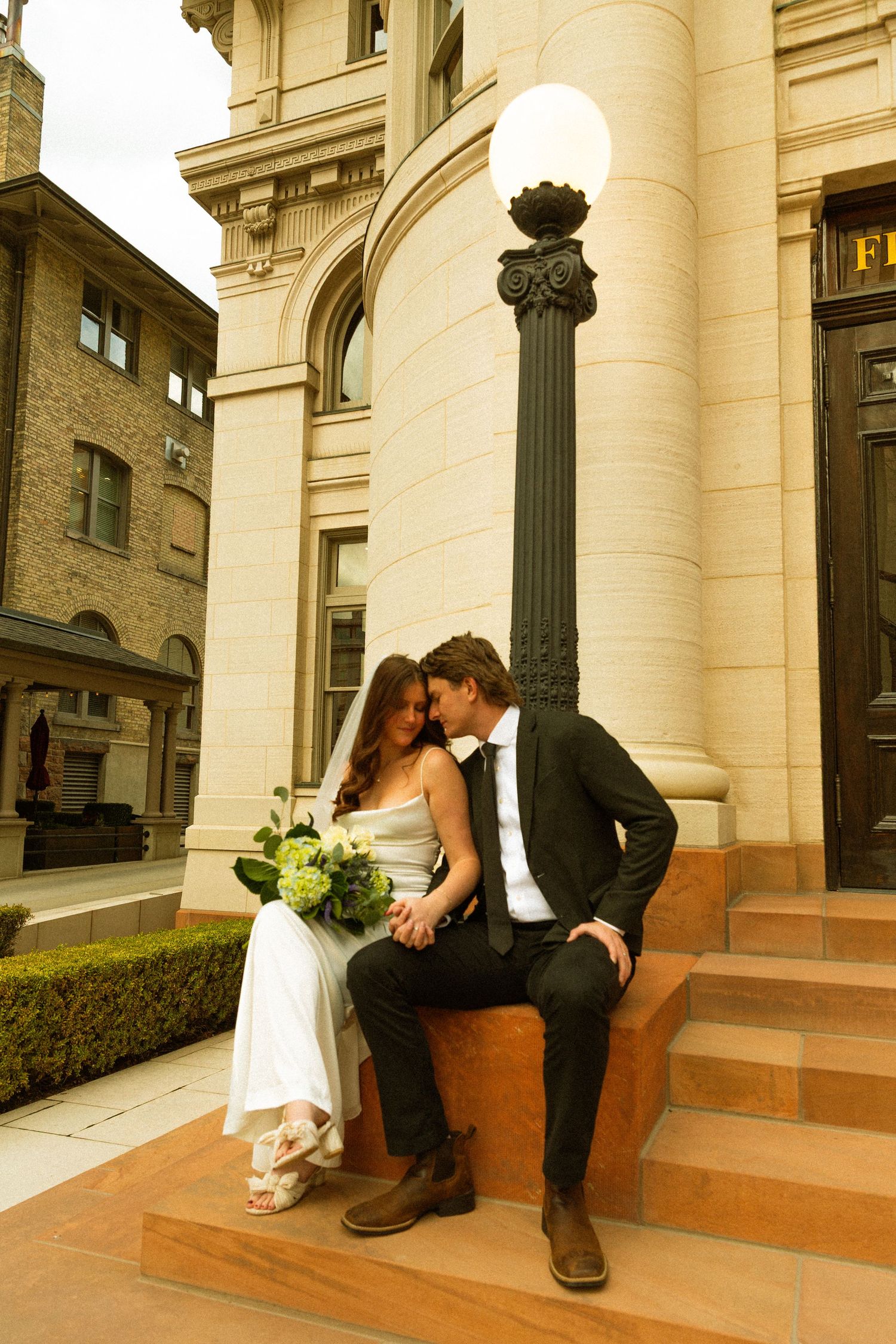 A romantic wedding couple shares intimate moments on stone steps in a series of sepia-toned photographs.