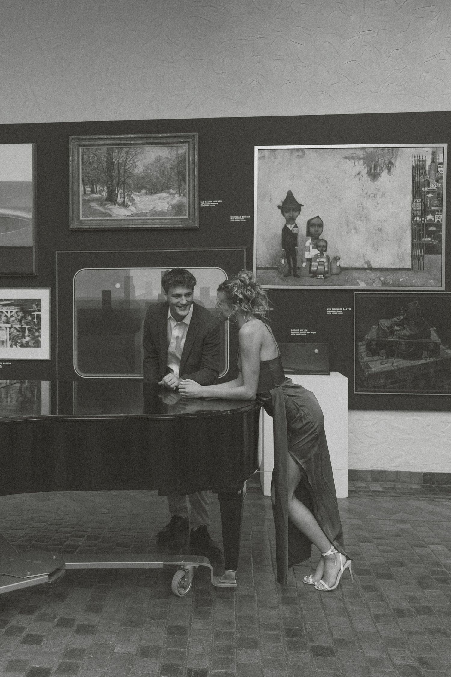 A sequence of black and white photos showing people setting up an art gallery exhibition space.