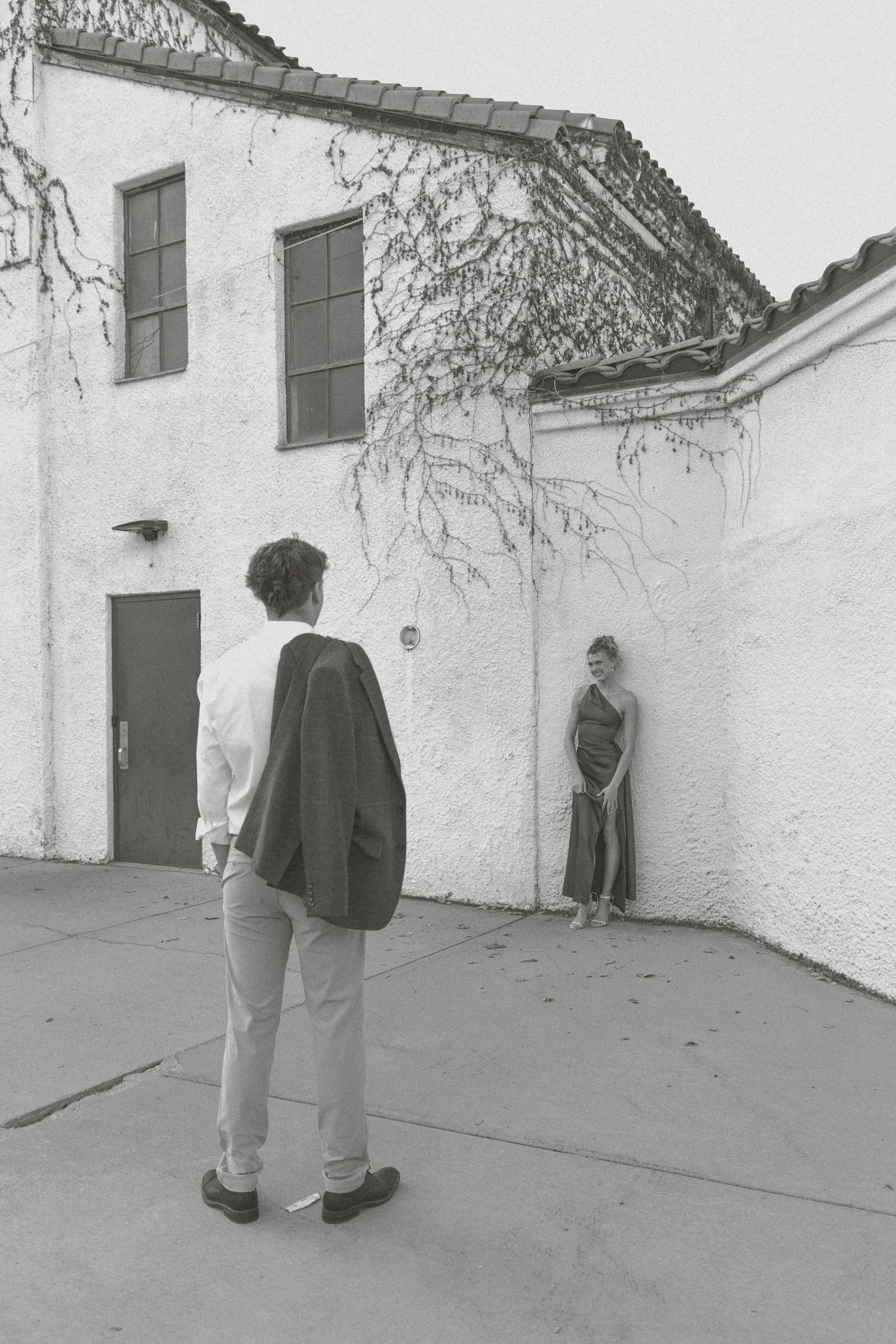 Black and white photo sequence showing two people in dark clothing walking and standing near white building walls.