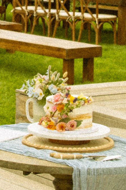 Elegant floral centerpieces displayed on rustic wooden tables at outdoor reception.