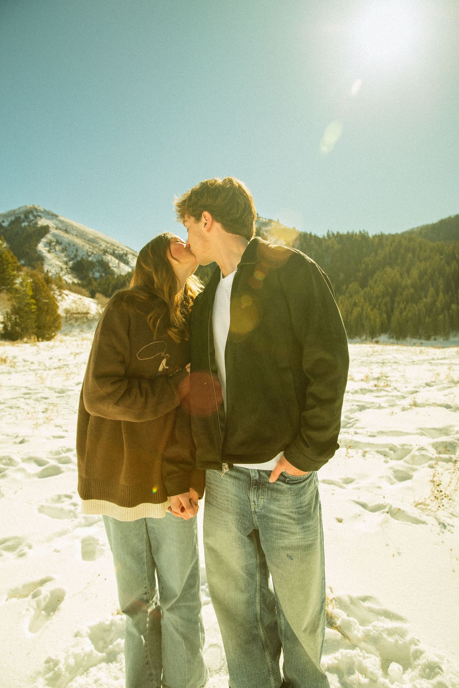 A romantic winter moment shared between a couple in the snowy mountains on a bright sunny day.