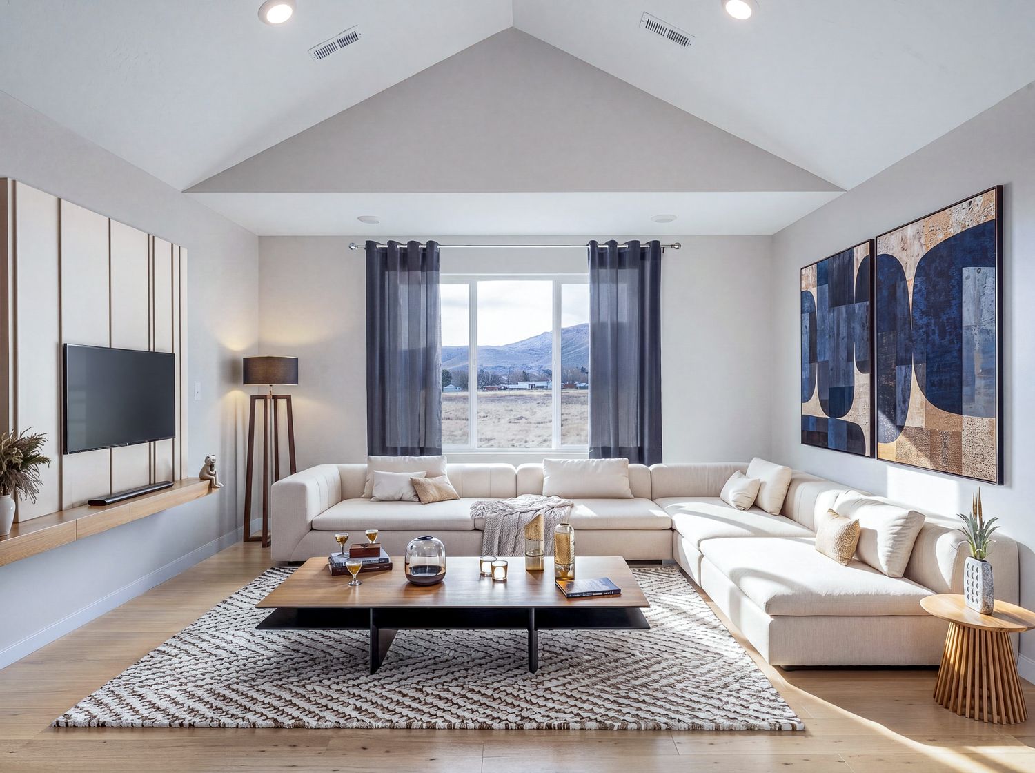 Contemporary living room with vaulted ceiling, white sectional, abstract art, and mountain view.