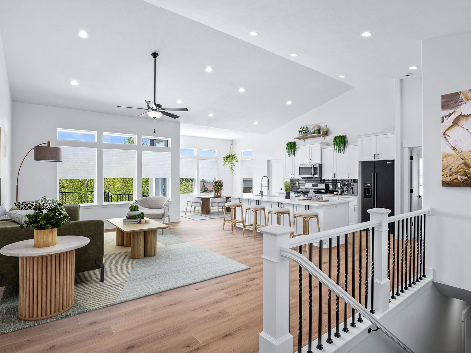Open-concept living room and kitchen with vaulted ceiling, hardwood floors, and staircase.