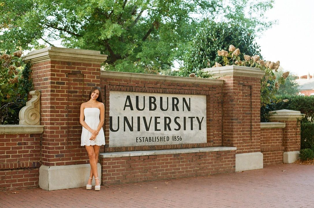 Auburn University entrance sign mounted on a brick wall with landscaping.