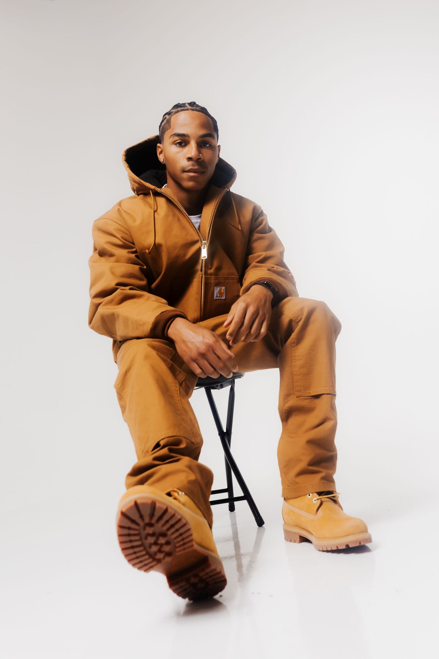 Model poses in tan workwear outfit and brown boots against white backdrop in three dynamic studio shots.