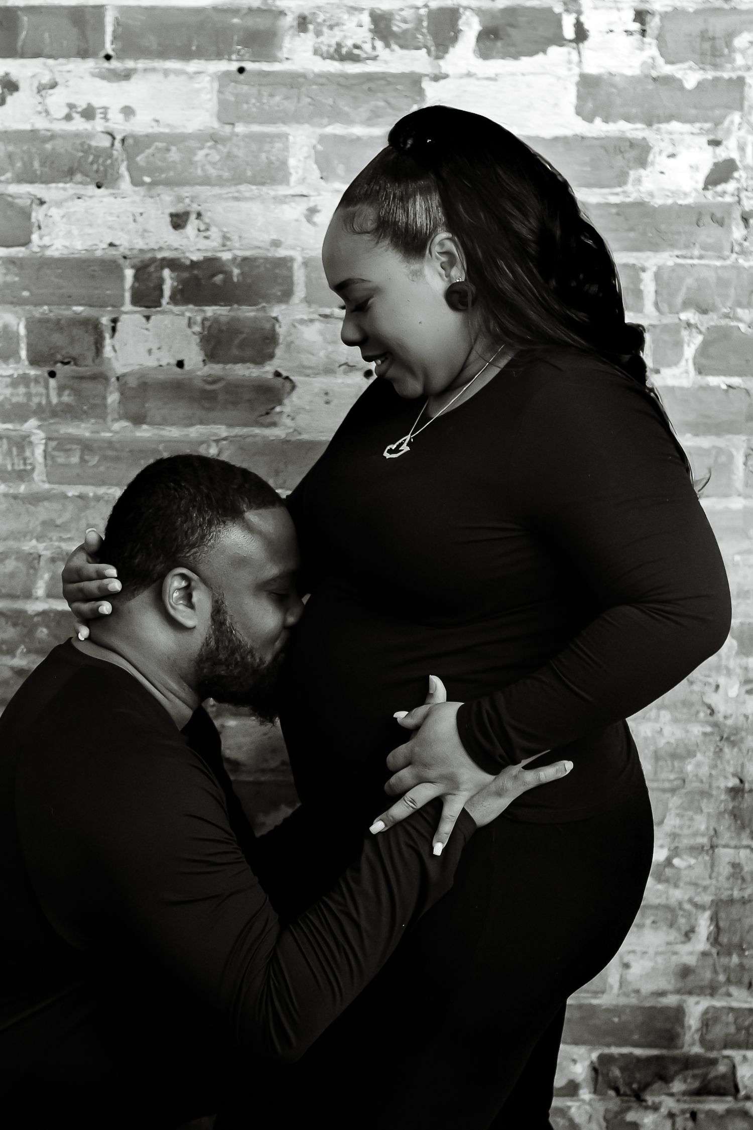 A black and white photo series showing intimate moments between two people against a brick wall background.