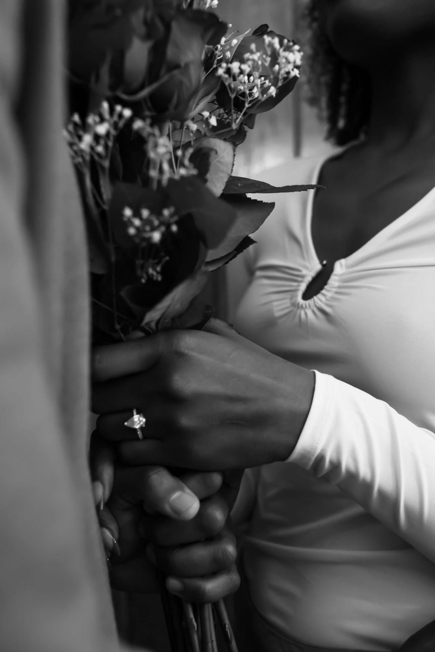 Artistic black and white close-up photo showing hands and formal attire details.