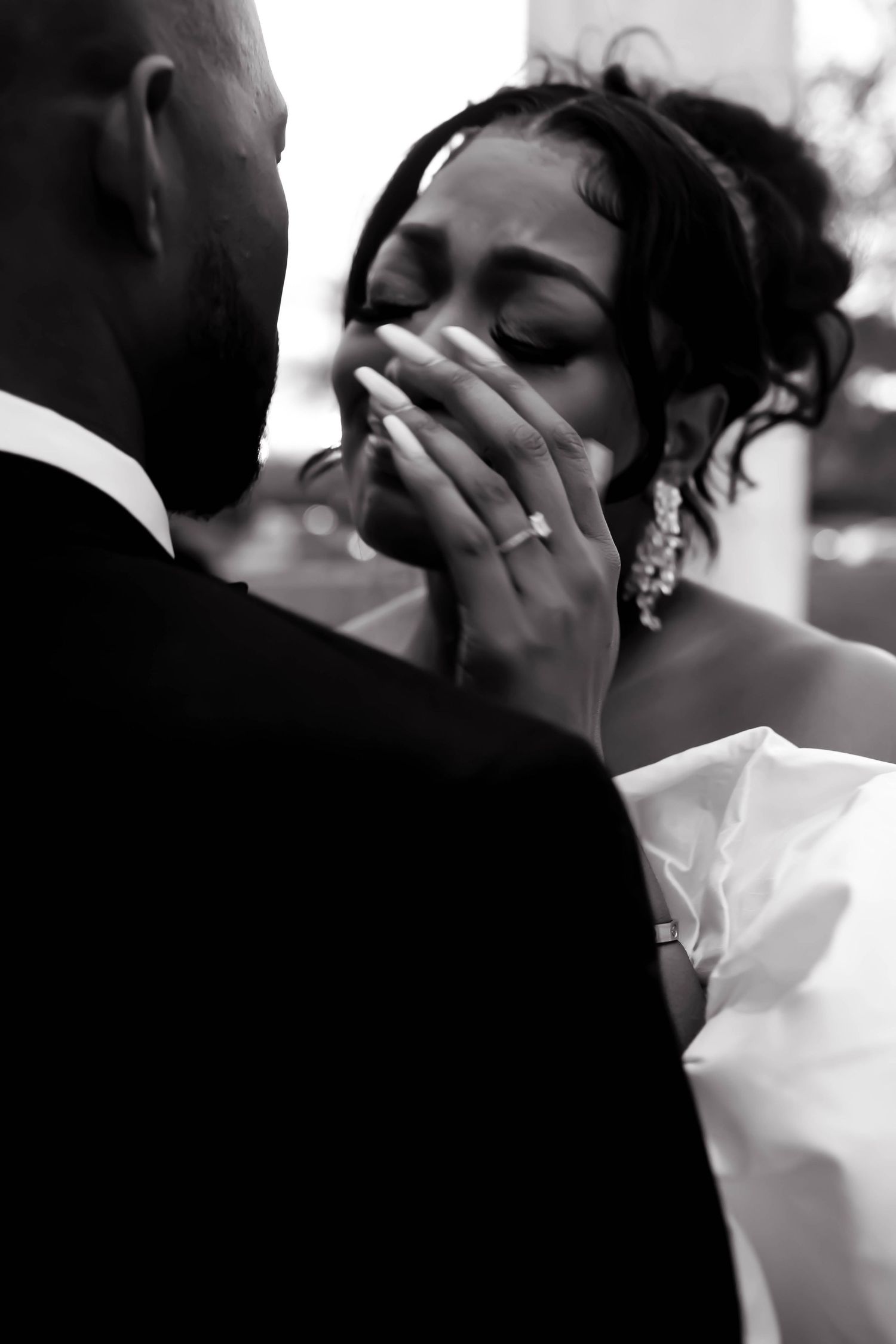 Intimate black and white wedding moment captured between couple near white columns.