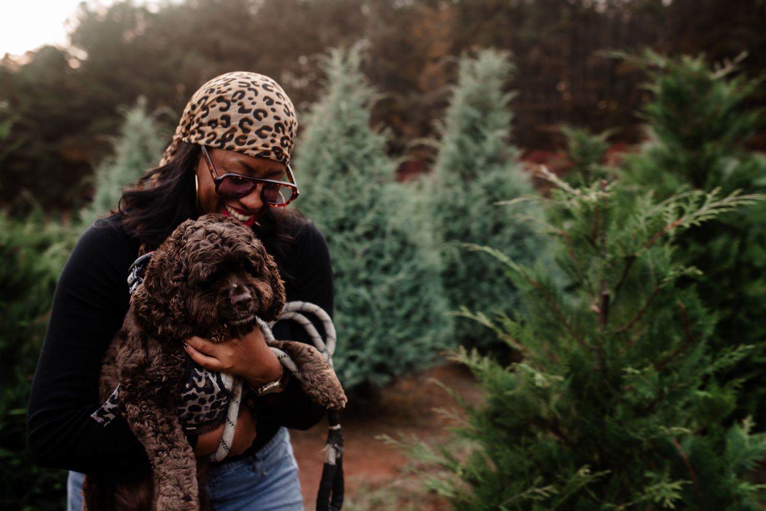 A candid family moment captured outdoors among evergreen trees in the background.
