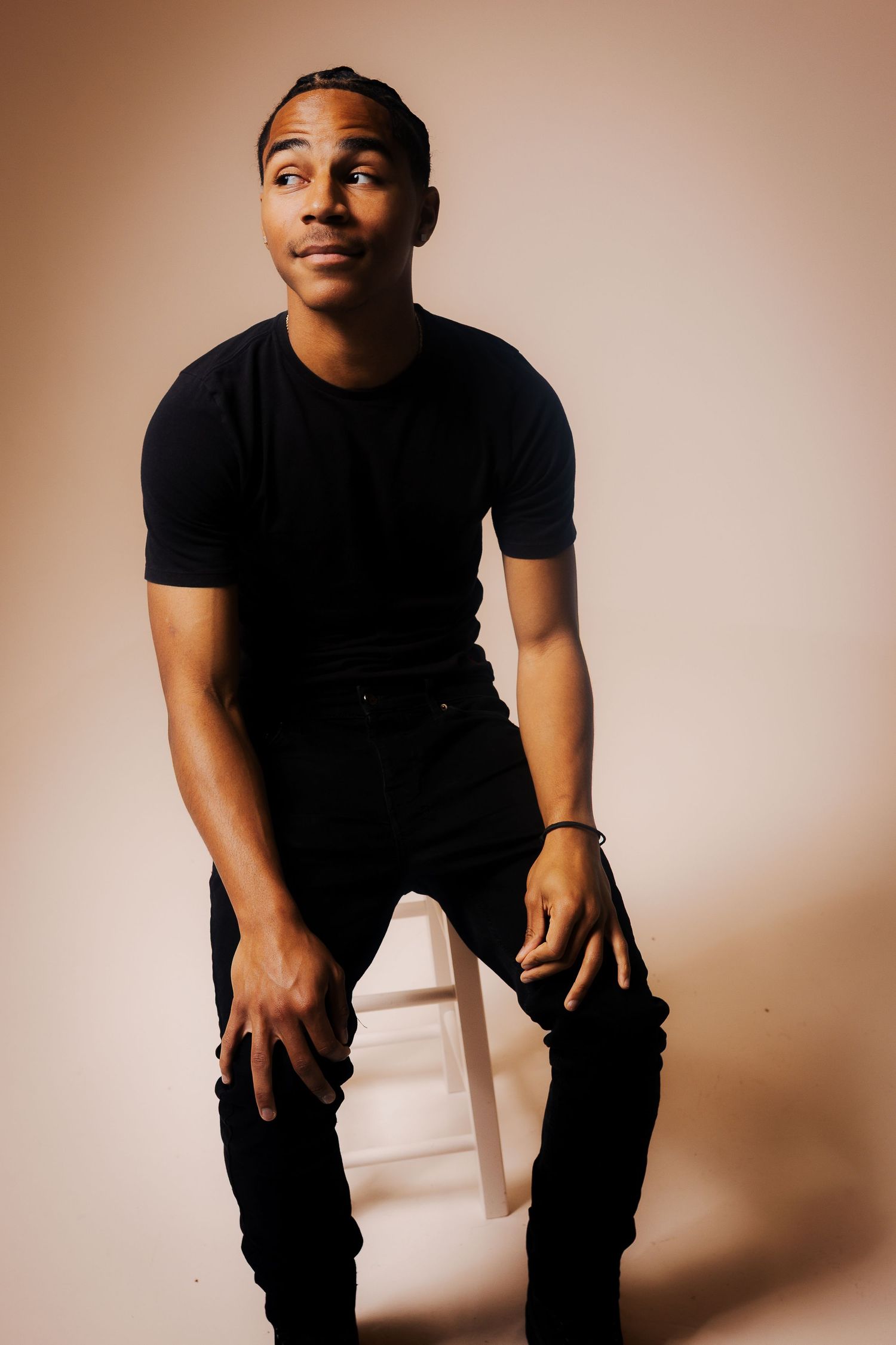 A series of studio portraits showing a person in black clothing against a warm beige background in different dynamic poses.