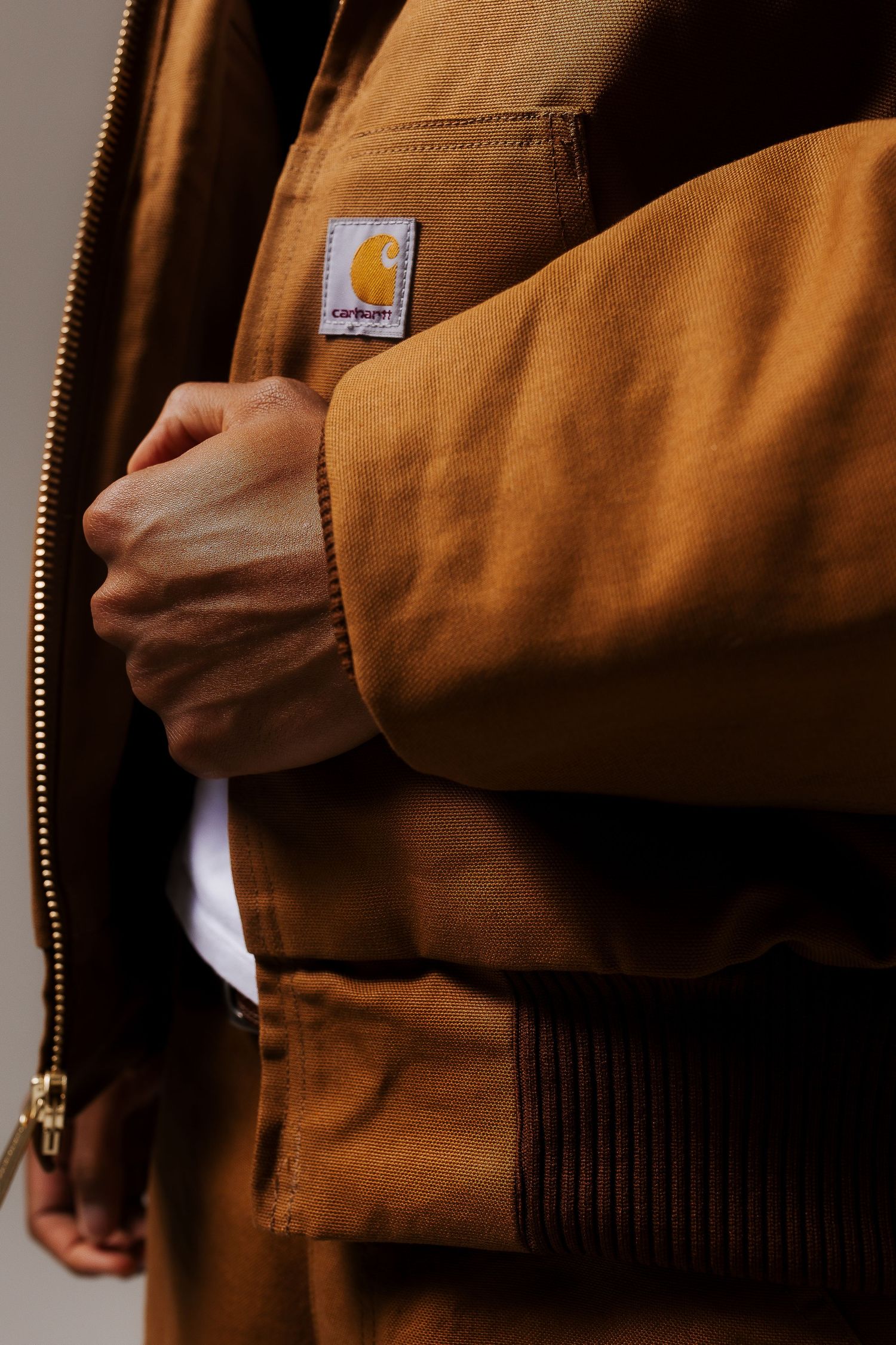 Close-up details of a brown Carhartt work jacket showing texture and zipper.