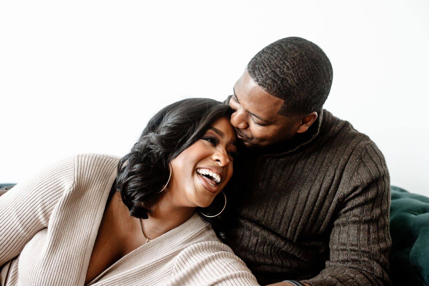 Candid moments of joy and laughter shared on a dark teal couch.