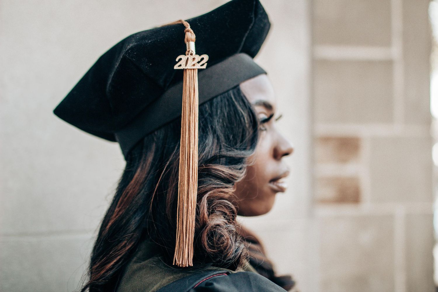 Graduate students in black caps and gowns with gold tassels celebrate during commencement ceremony.