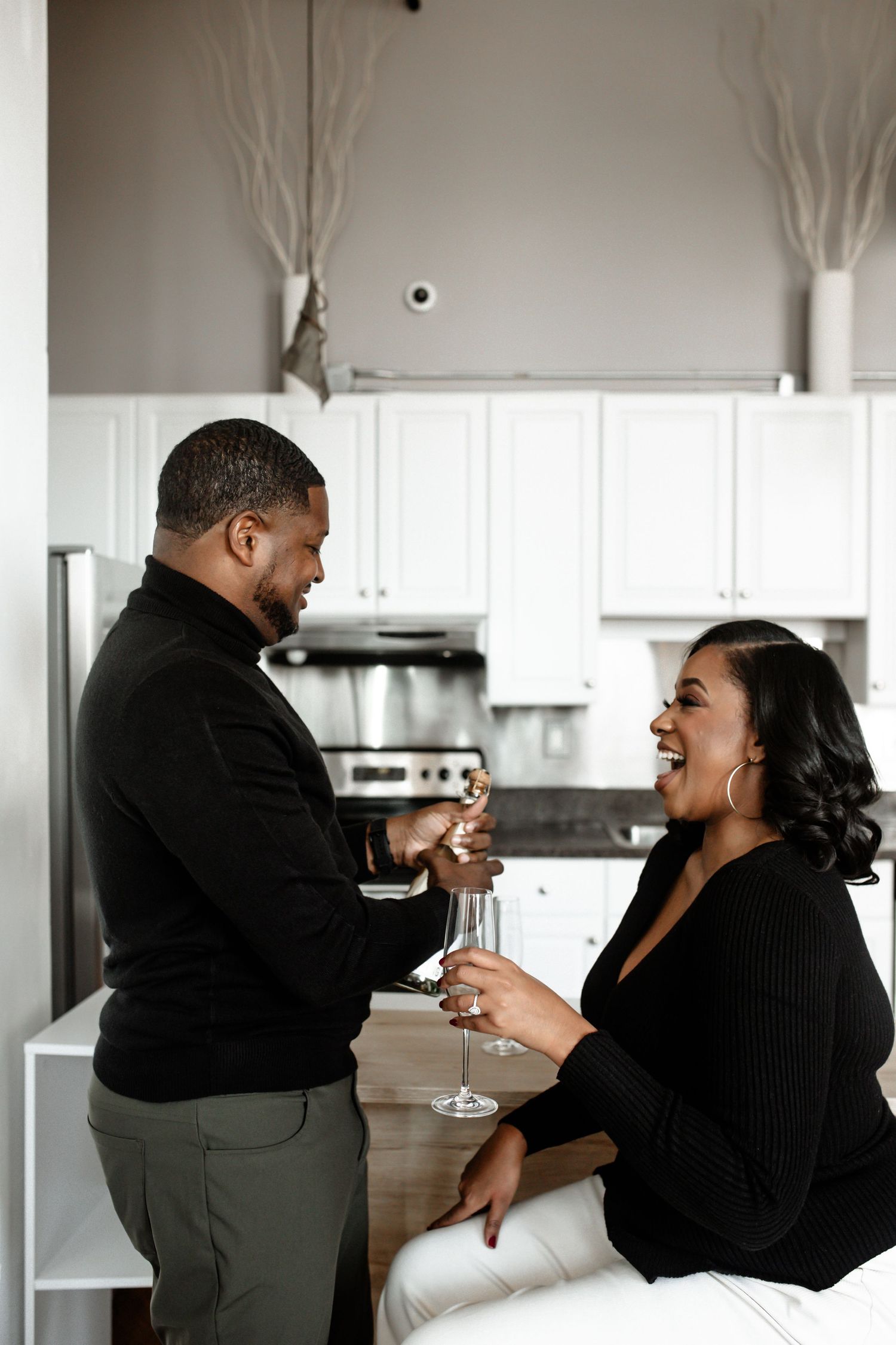 A couple sharing joyful moments and laughter in a modern white kitchen.