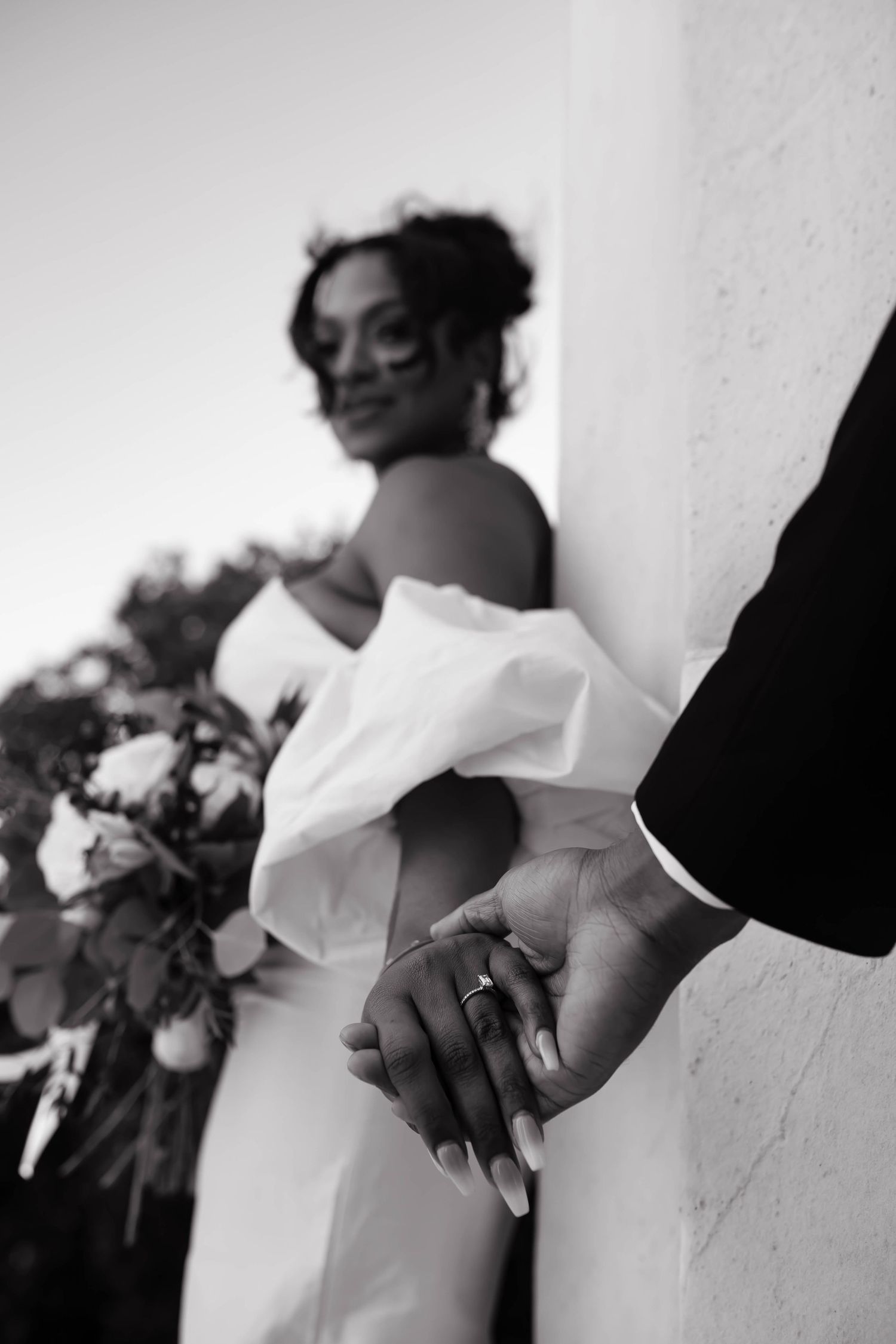 Close-up black and white photo of hands clasped together in an intimate moment.