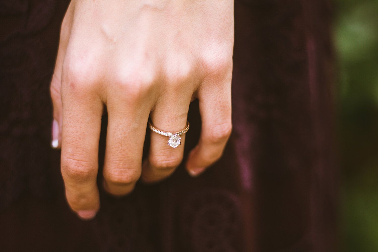 Close-up view of hands with wedding rings exchanging vows during an outdoor ceremony.
