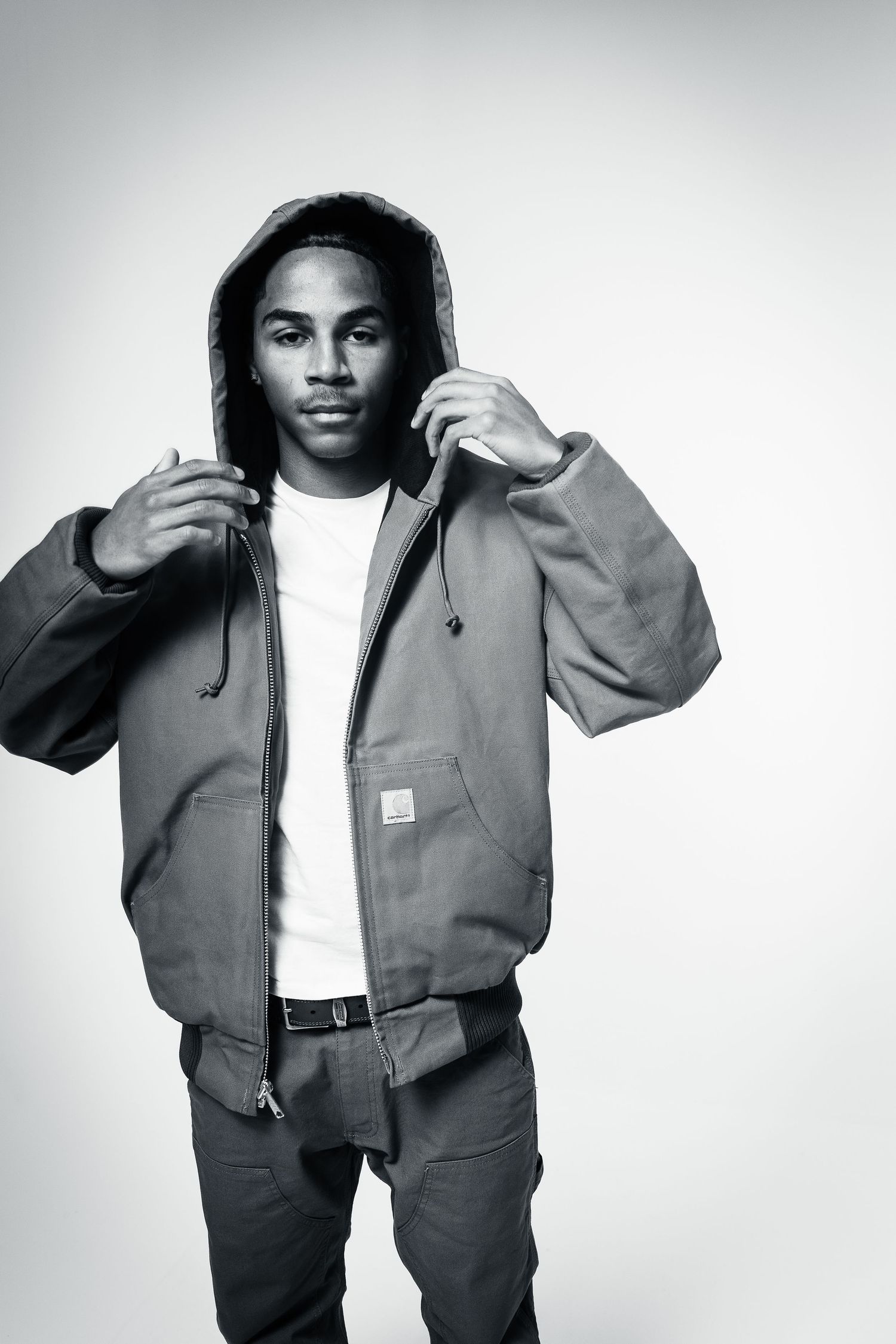 Black and white fashion photo series showing a person modeling a casual workwear jacket and pants outfit.