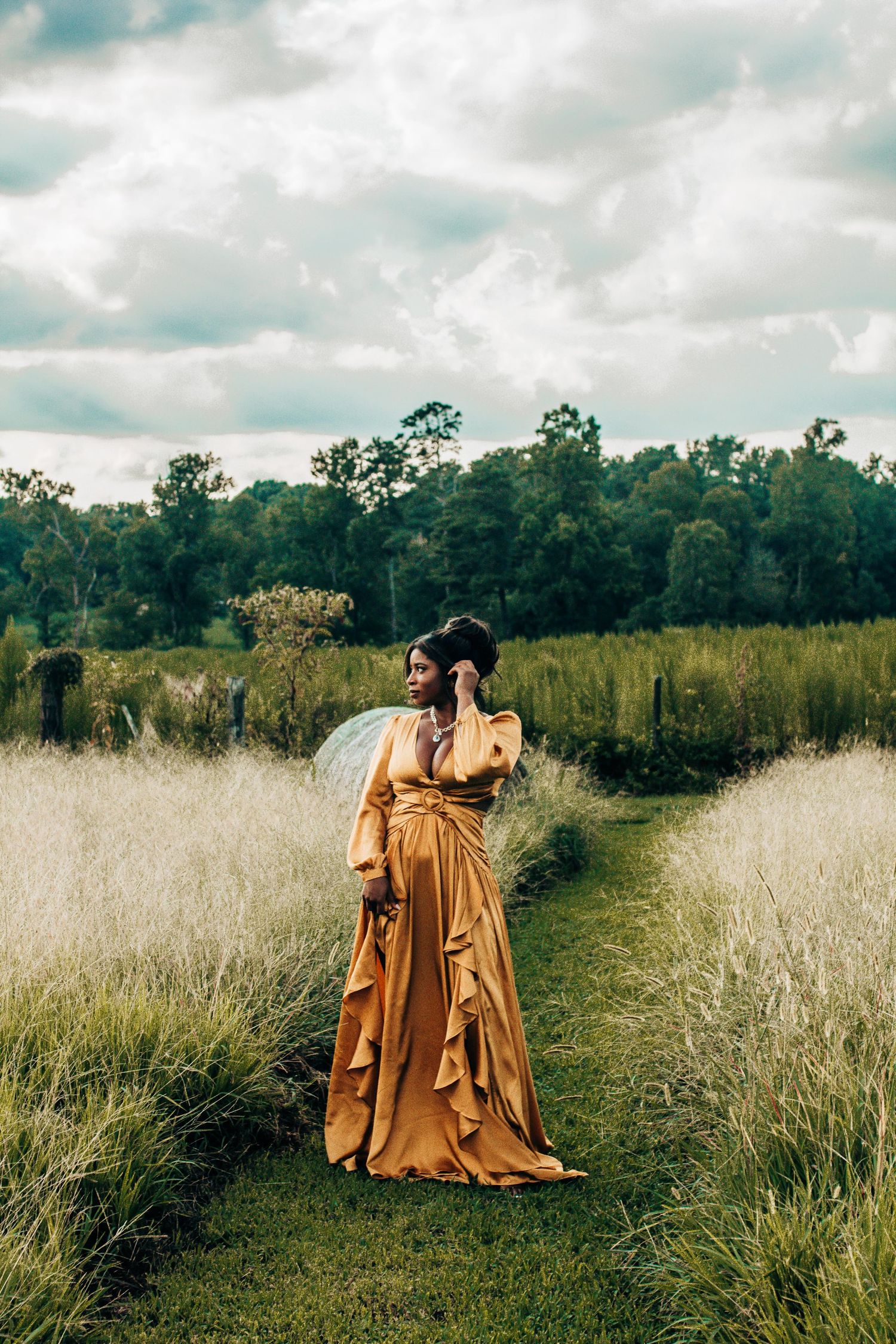 Two figures in flowing golden dresses dance together in a misty field with trees in the background.