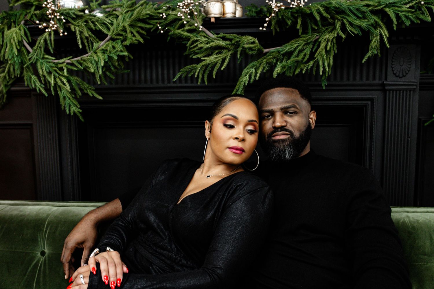 A romantic engagement photo session showing a couple embracing against a dark background with greenery.