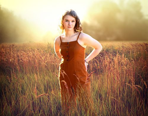 Senior portrait in Papillion, NE — student smiling in golden-hour light in a field.