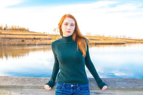Calm lakeside senior photo with relaxed posing and natural tones