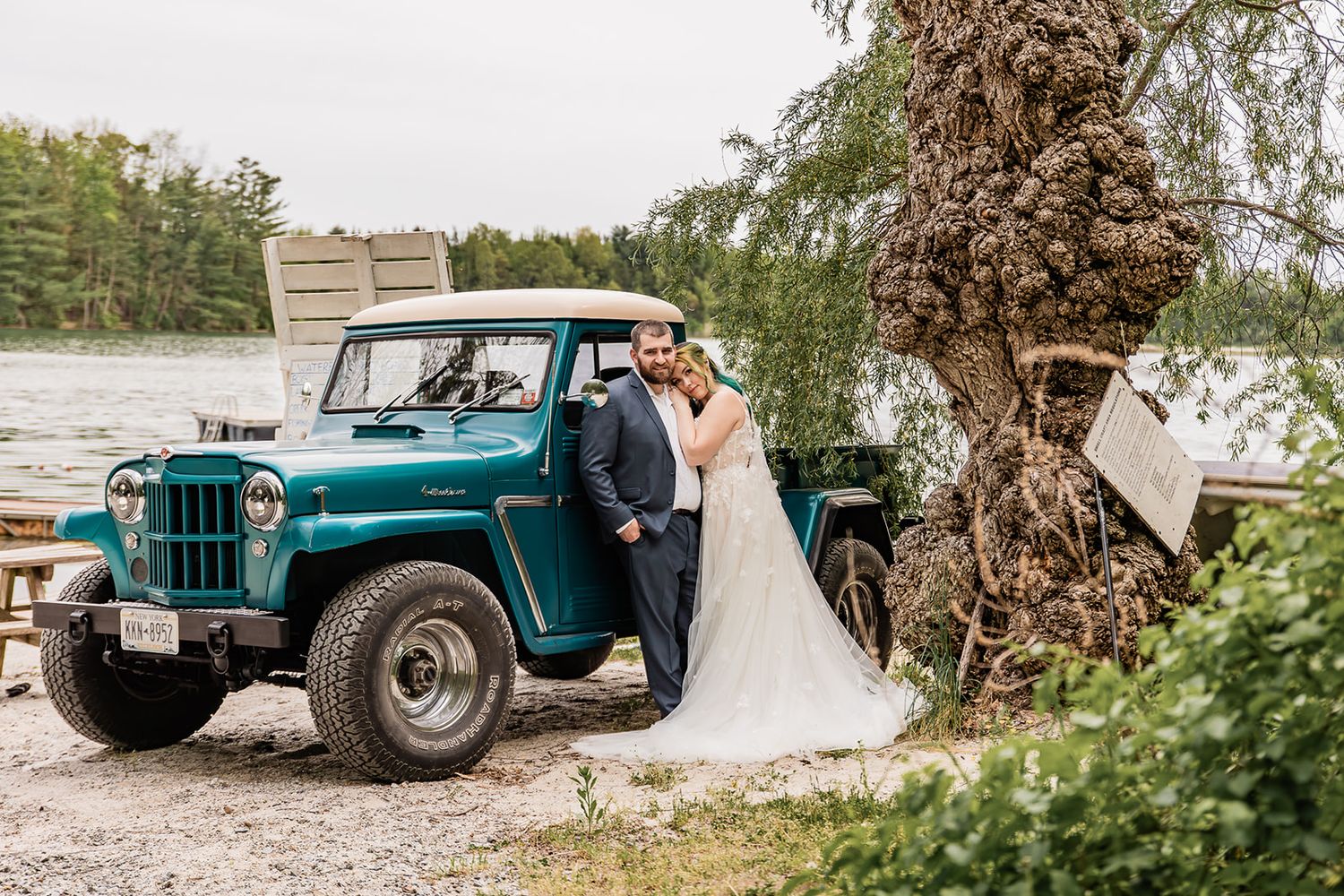 A vintage teal pickup truck serves as a rustic backdrop for wedding photos in a natural setting.