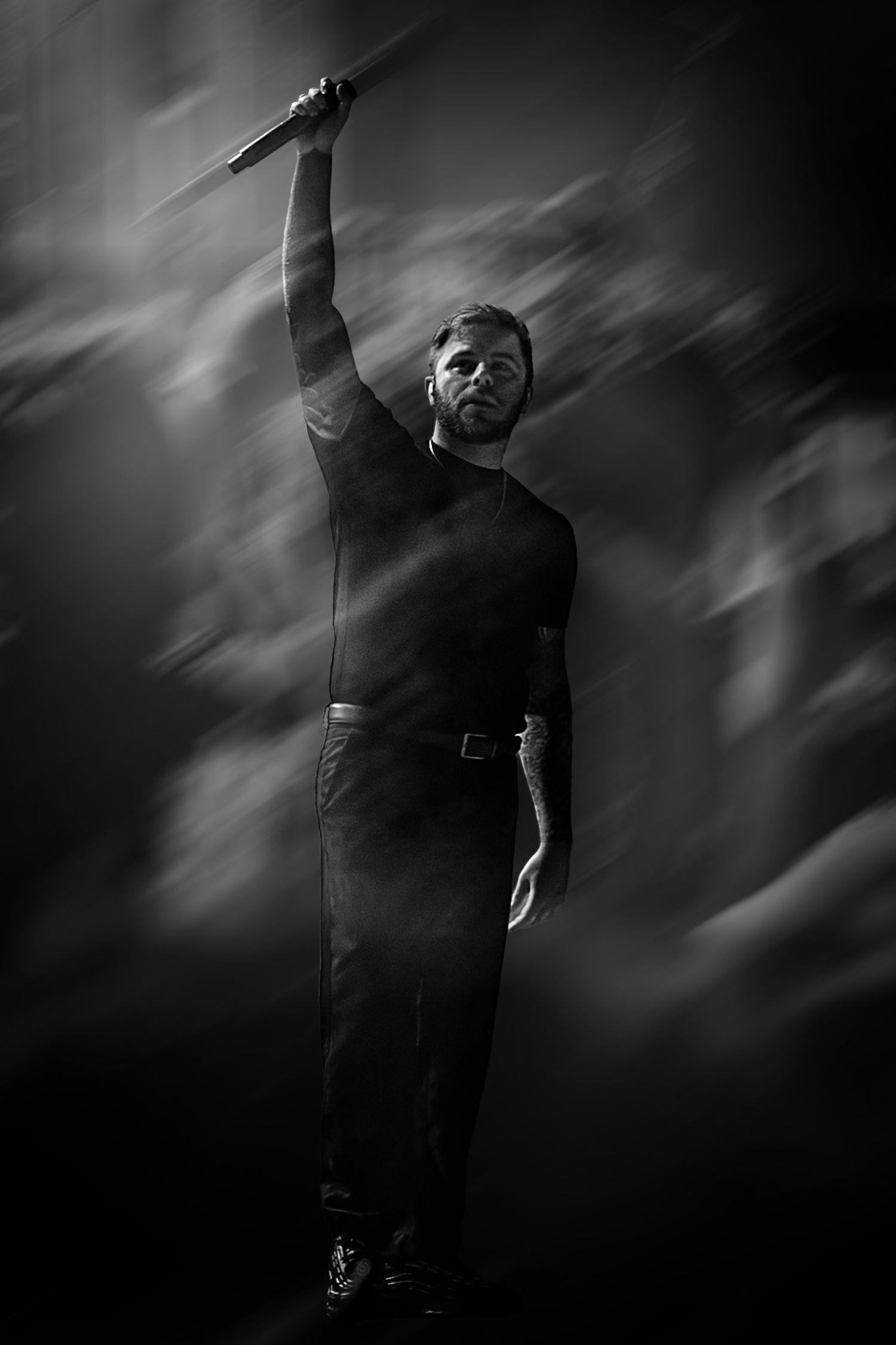 Black and white photo of a man in dark clothing raising a sword dramatically against a smoky background.