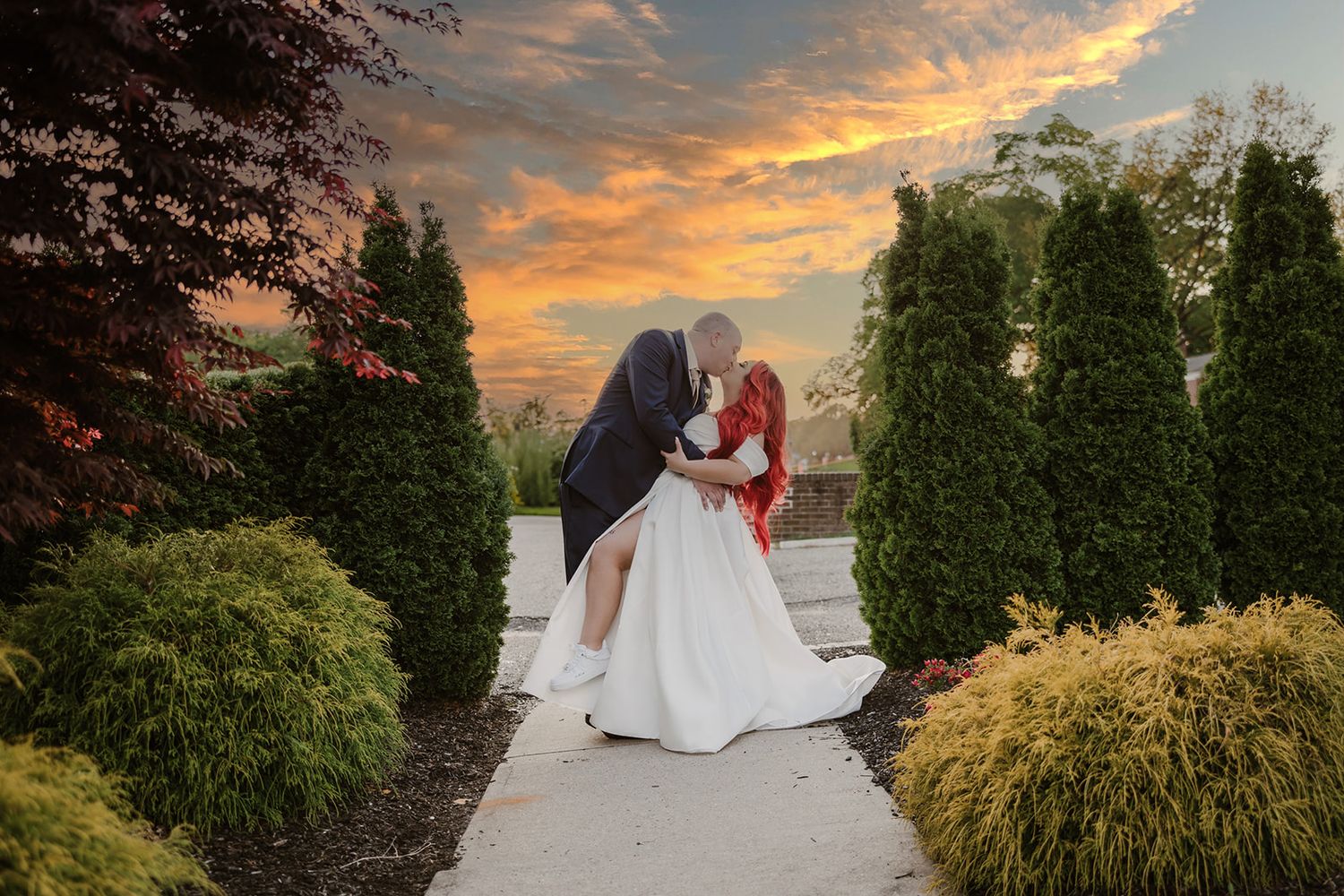 A romantic sunset wedding photoshoot featuring a flowing white dress against a colorful evening sky.