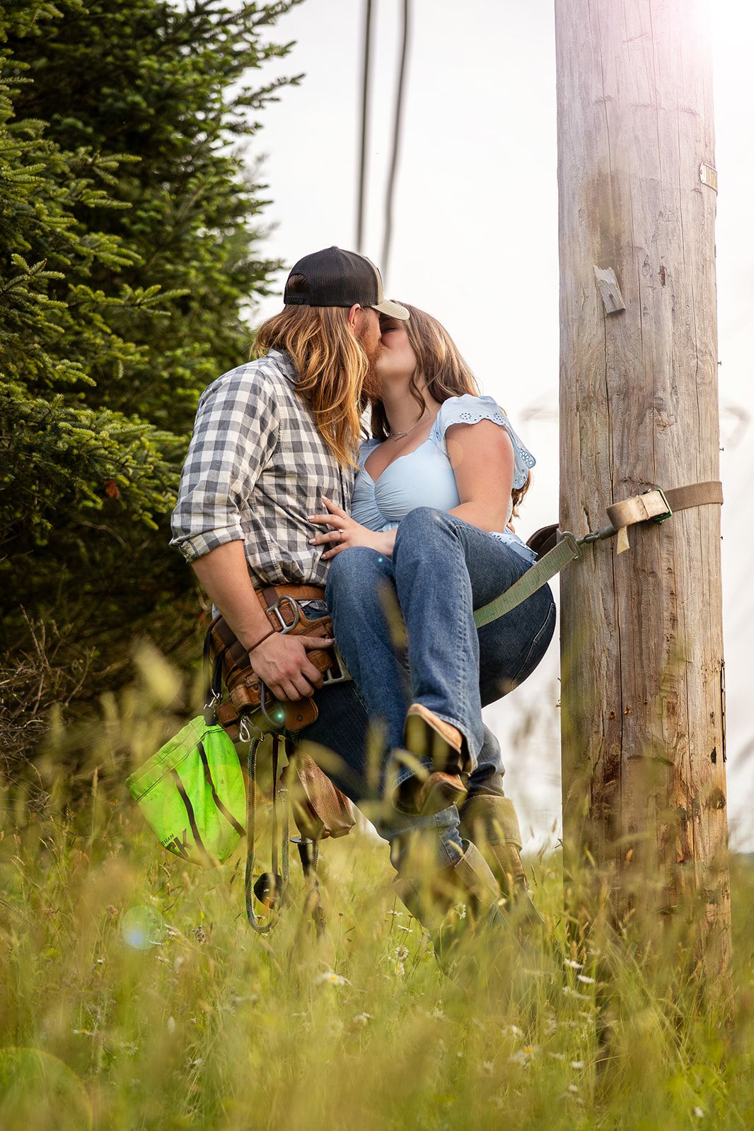Two people sharing an intimate moment while sitting on wooden posts in a meadow.