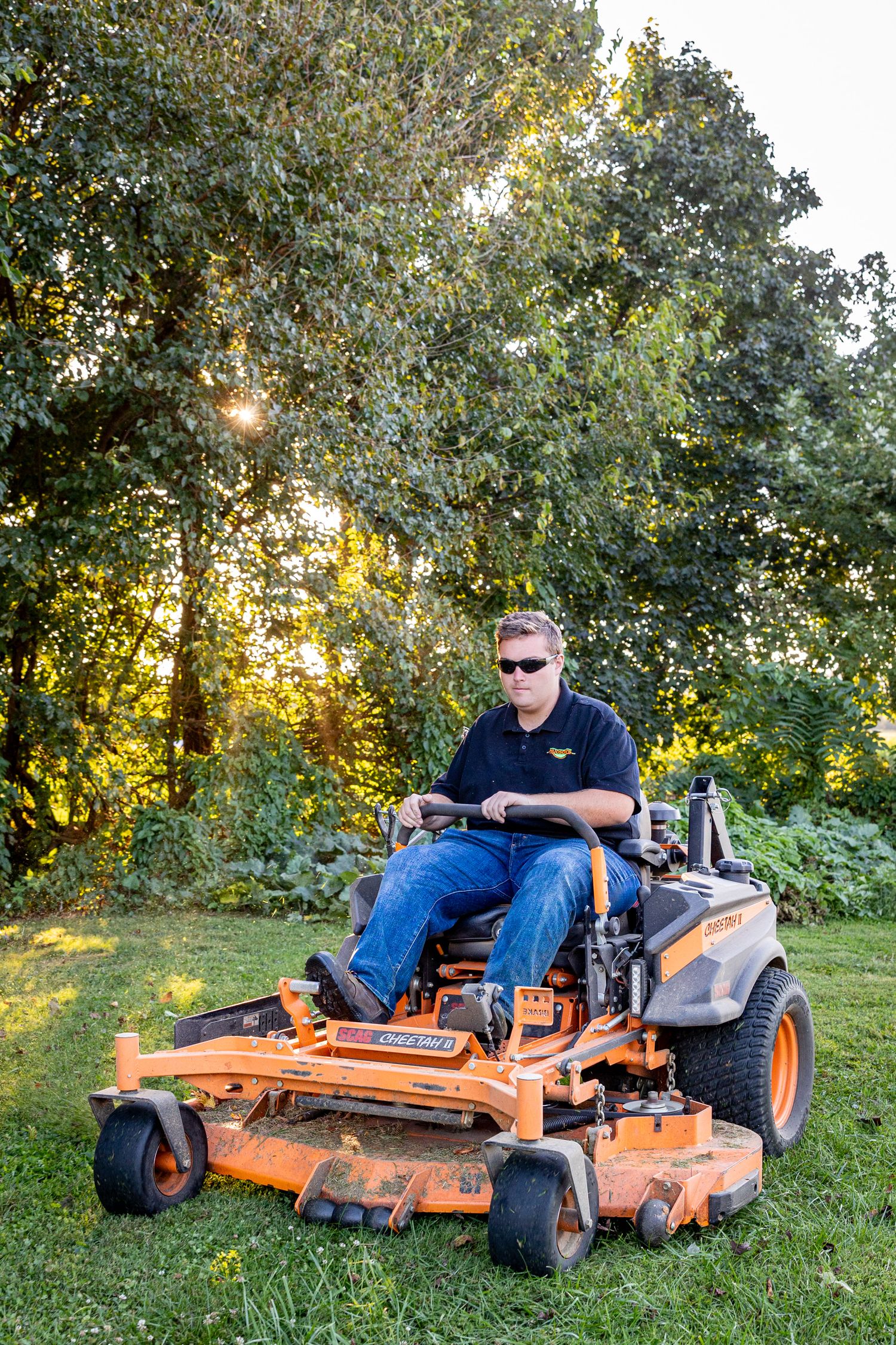 A zero-turn mower performs a sharp turn on green grass during lawn maintenance at sunset.