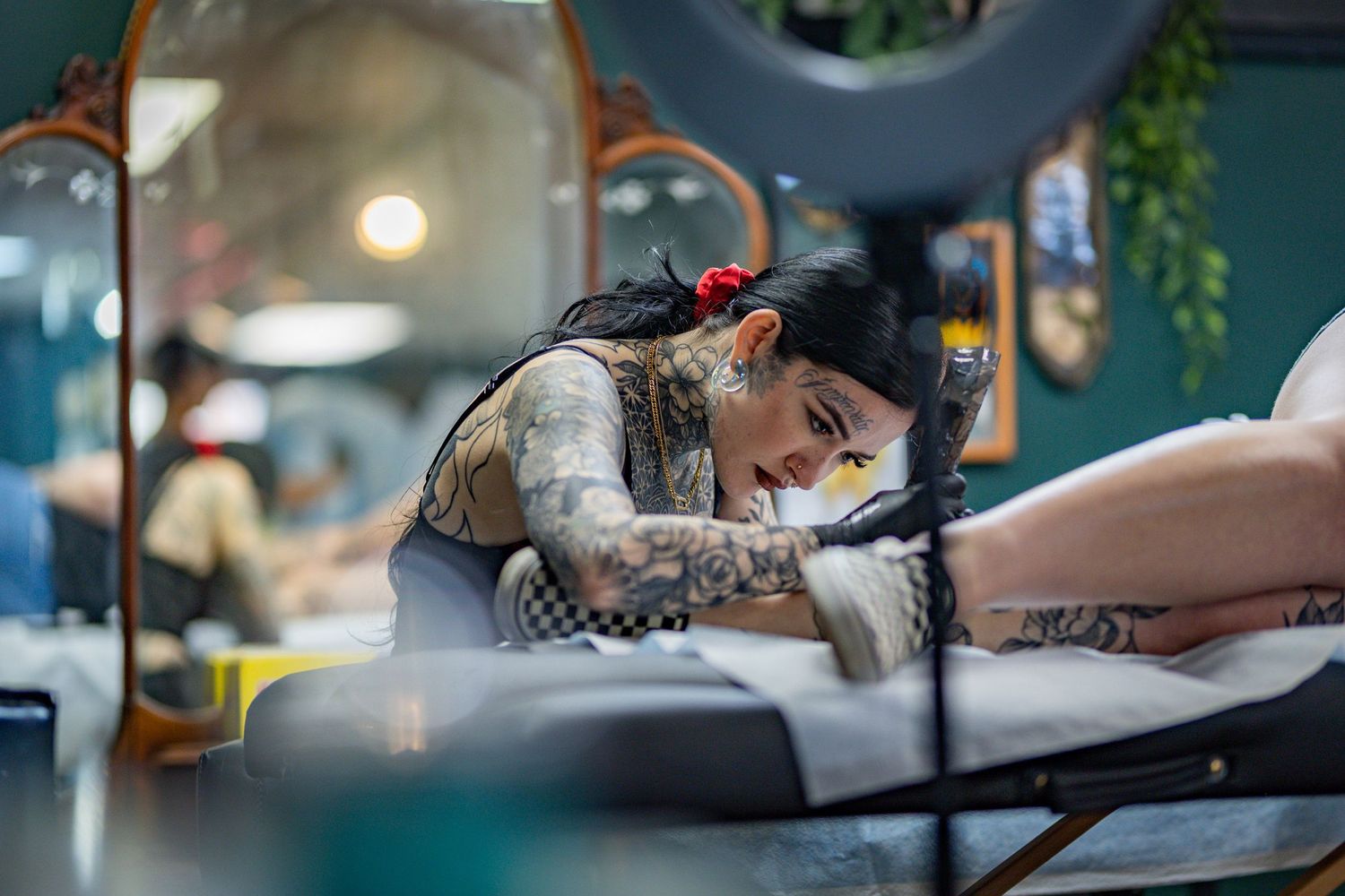 Professional tattoo artist carefully works on a detailed design in a modern studio setting.