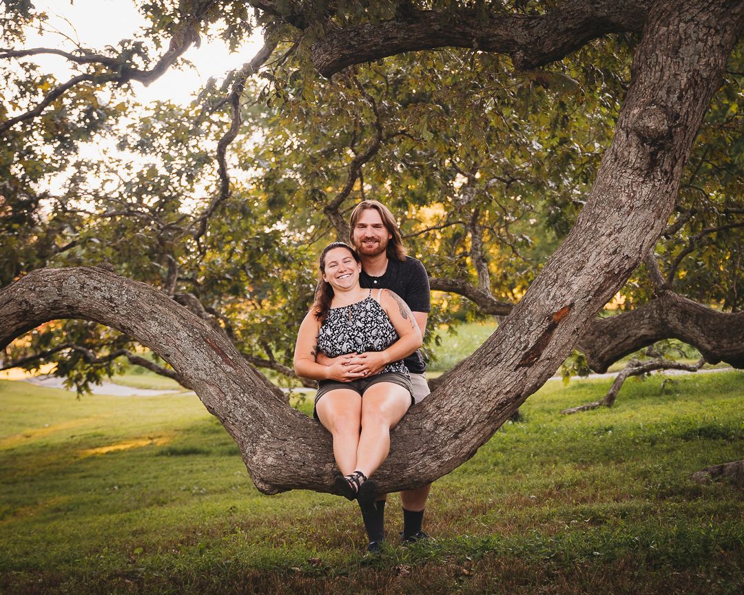 A large curved tree branch creates a natural frame for outdoor portrait photography.