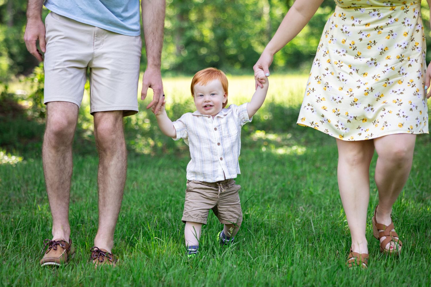 Family walking together through green grass on a sunny day.