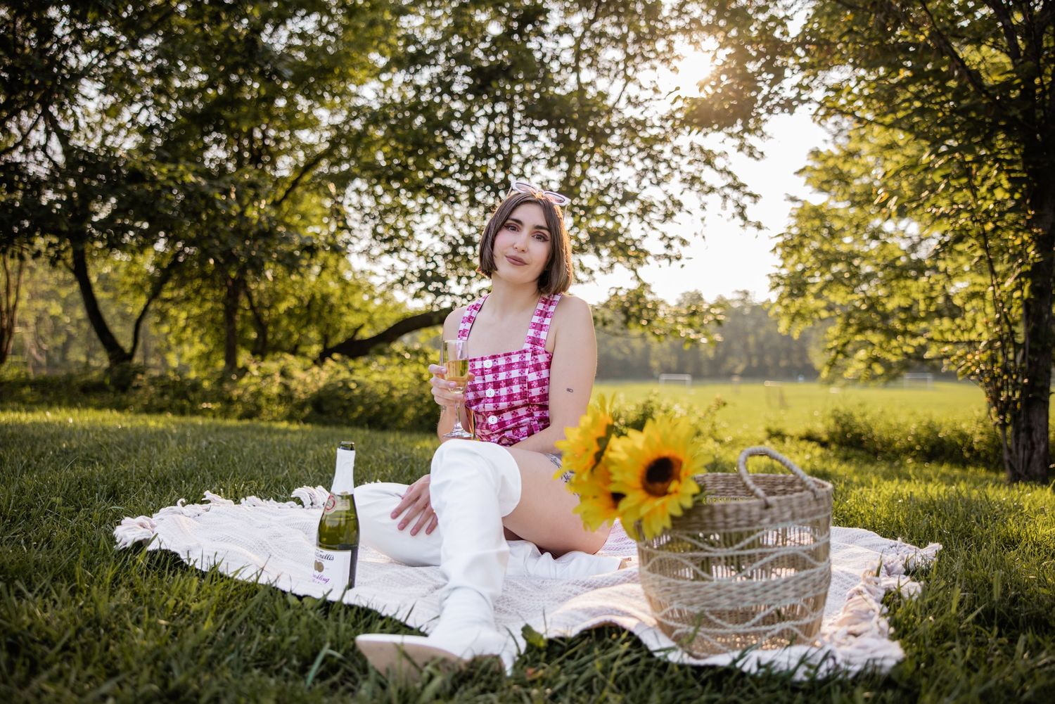 Outdoor photoshoot in a sunny field with white dress and sunflowers creating a dreamy summer scene.