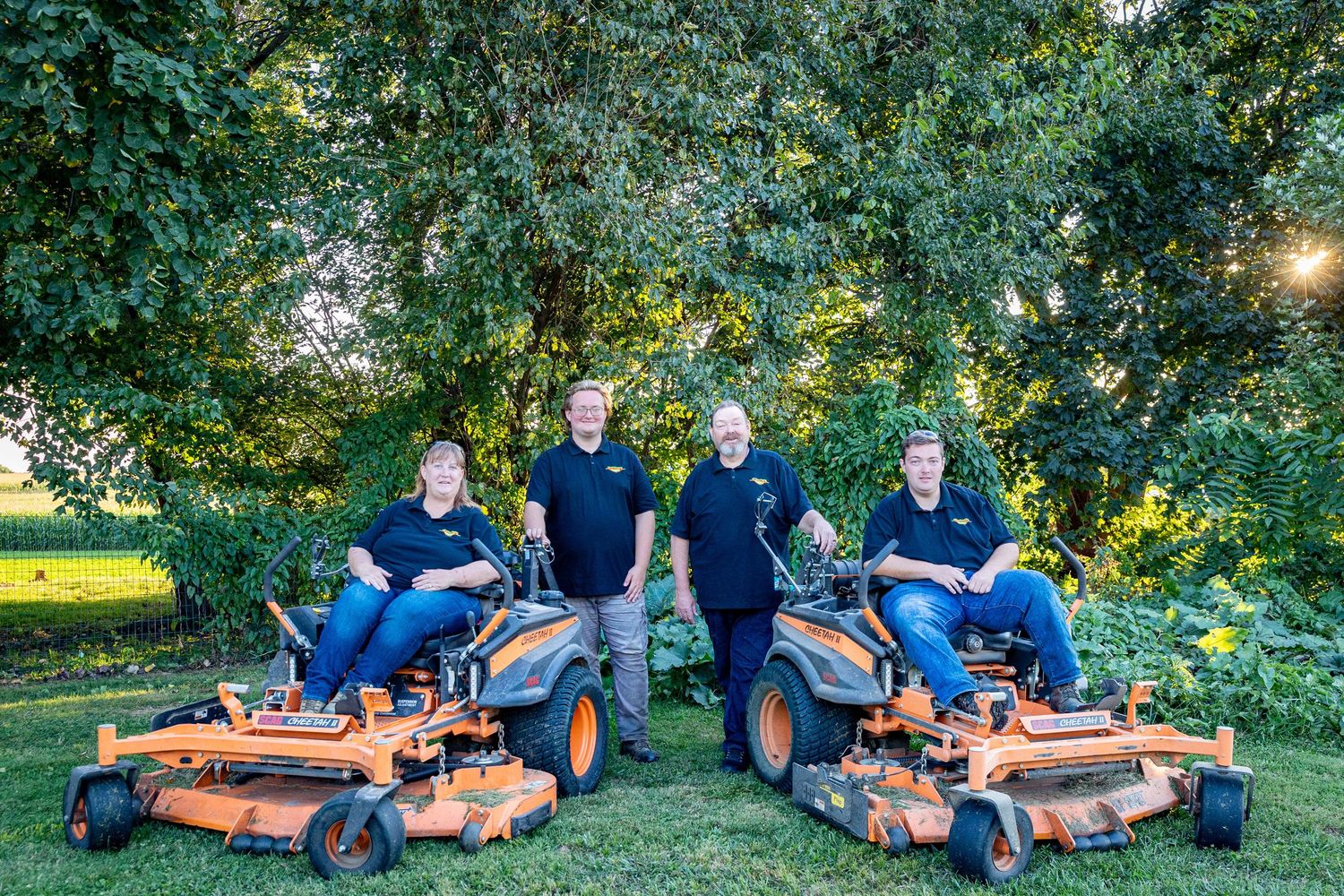 Family group photos on grass with orange lawn mowers in garden setting.