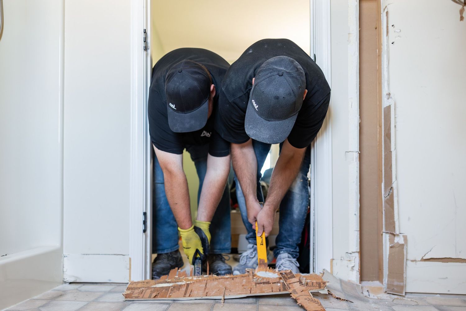 Workers install new hardwood flooring in a residential room during a home renovation project.
