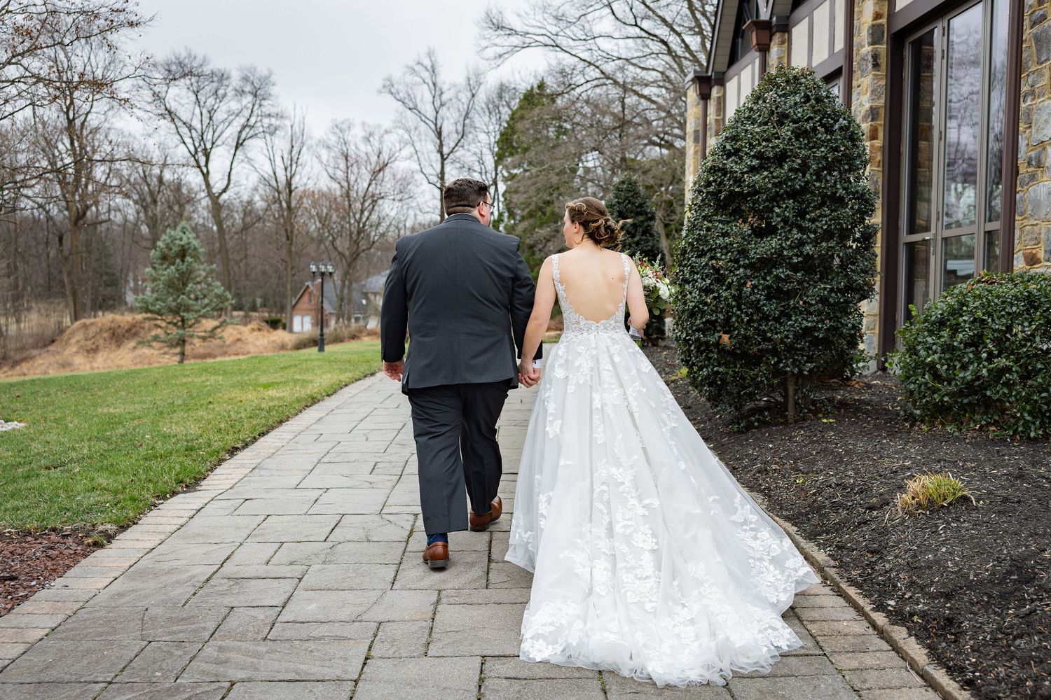 Newlyweds walking along a stone pathway surrounded by landscaping.