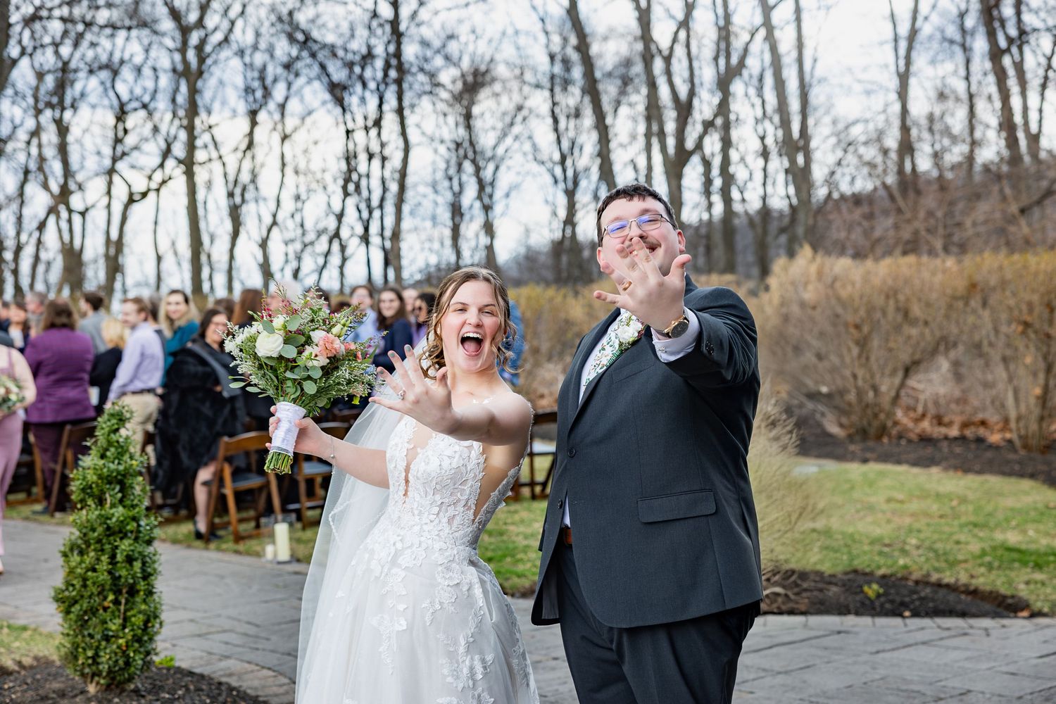Joyful wedding couple celebrating outdoors in a natural setting.