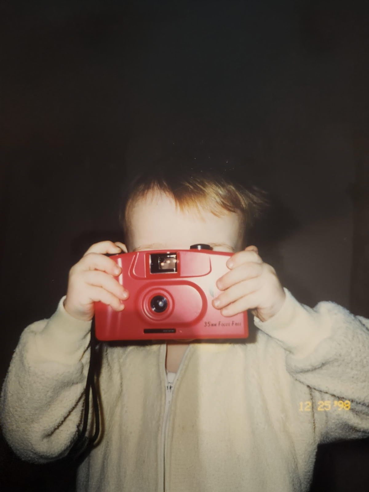 Sequence showing hands holding a vintage red point-and-shoot camera against white fabric.