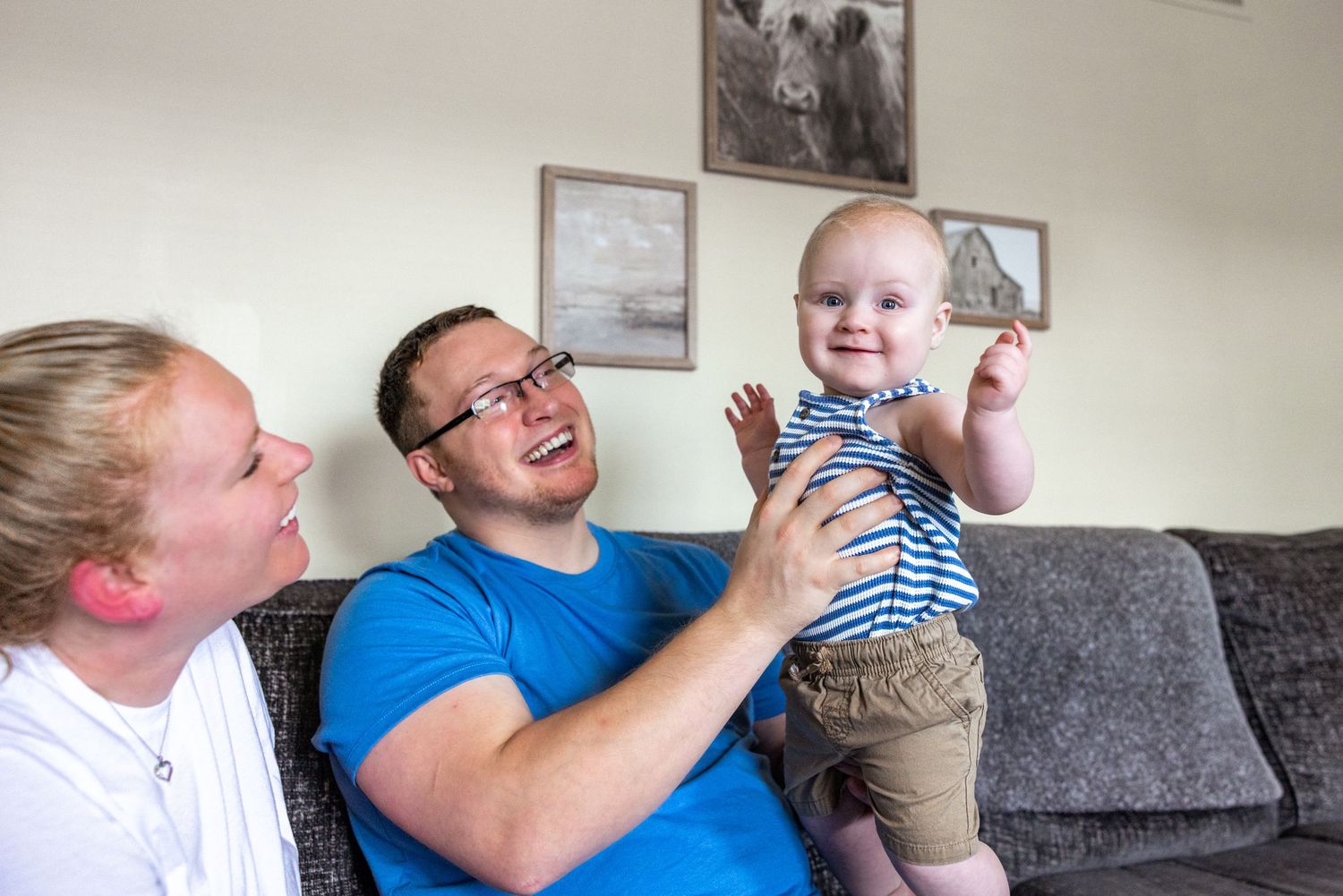 Family sharing playful moments together on a grey couch in living room.