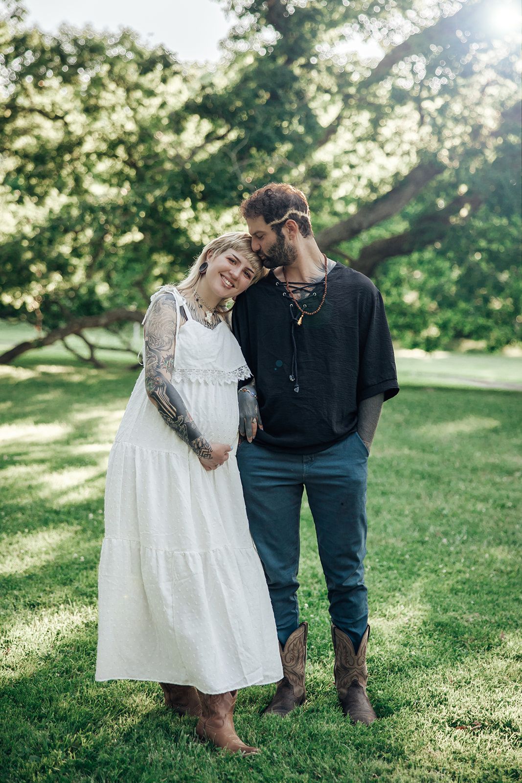 A couple in casual attire embracing on a sunlit grassy hillside.