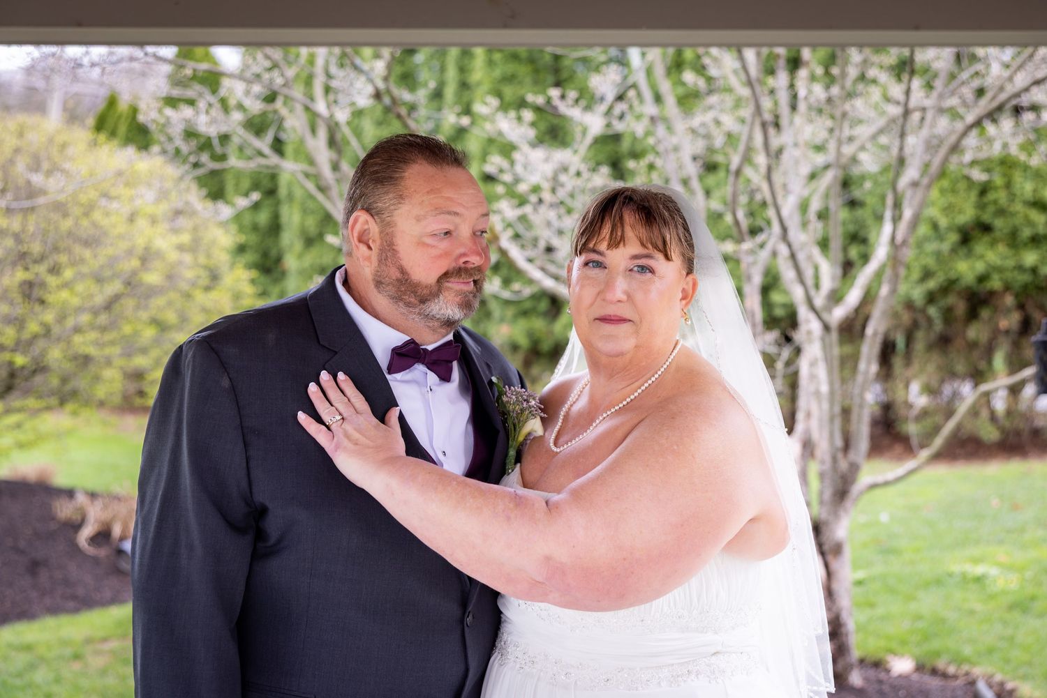 Couple in wedding attire sharing a romantic moment outdoors.