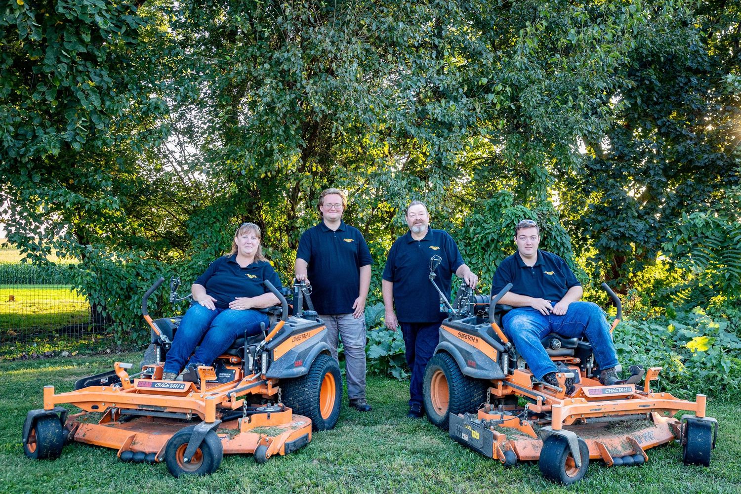 Group photo session with people lounging on vintage lawn mowers outdoors.