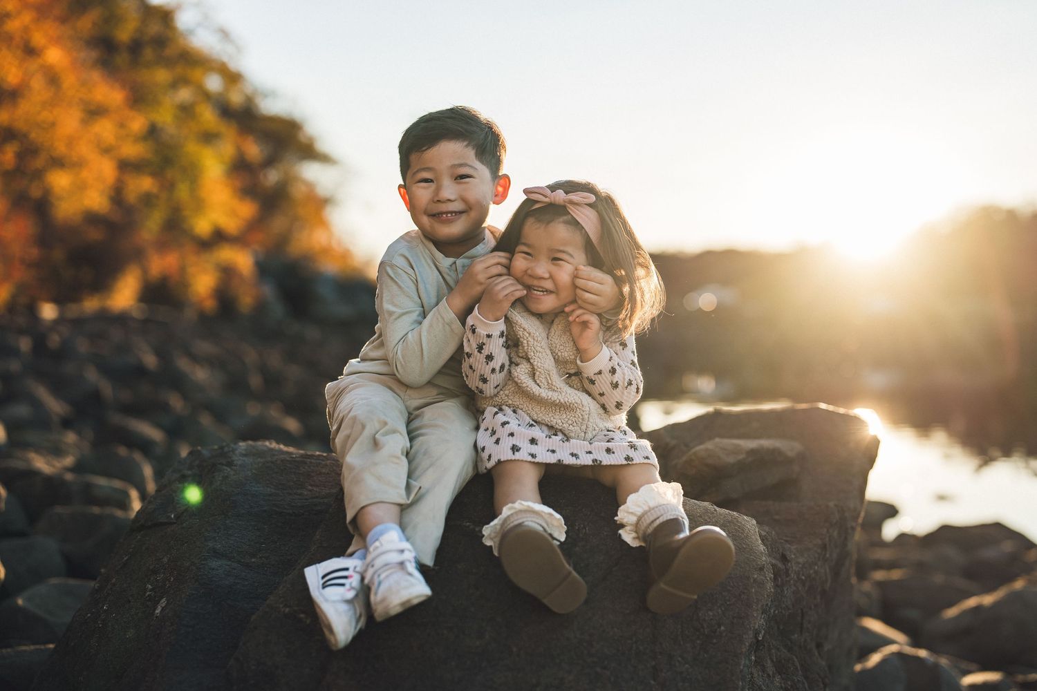 Candid family moment captured on coastal rocks during warm autumn sunset.