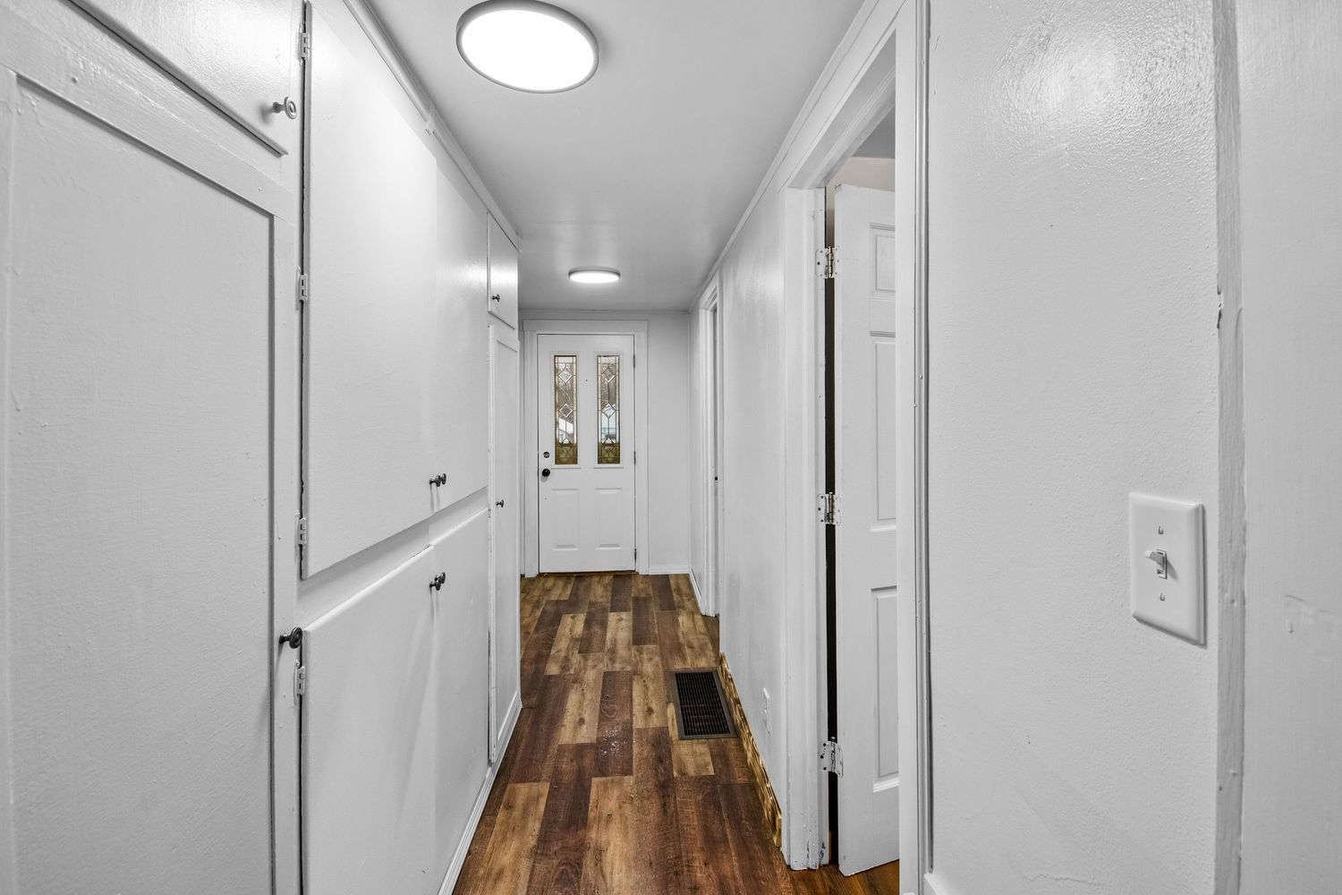 Bright white corridor with modern lighting fixtures and wood flooring.