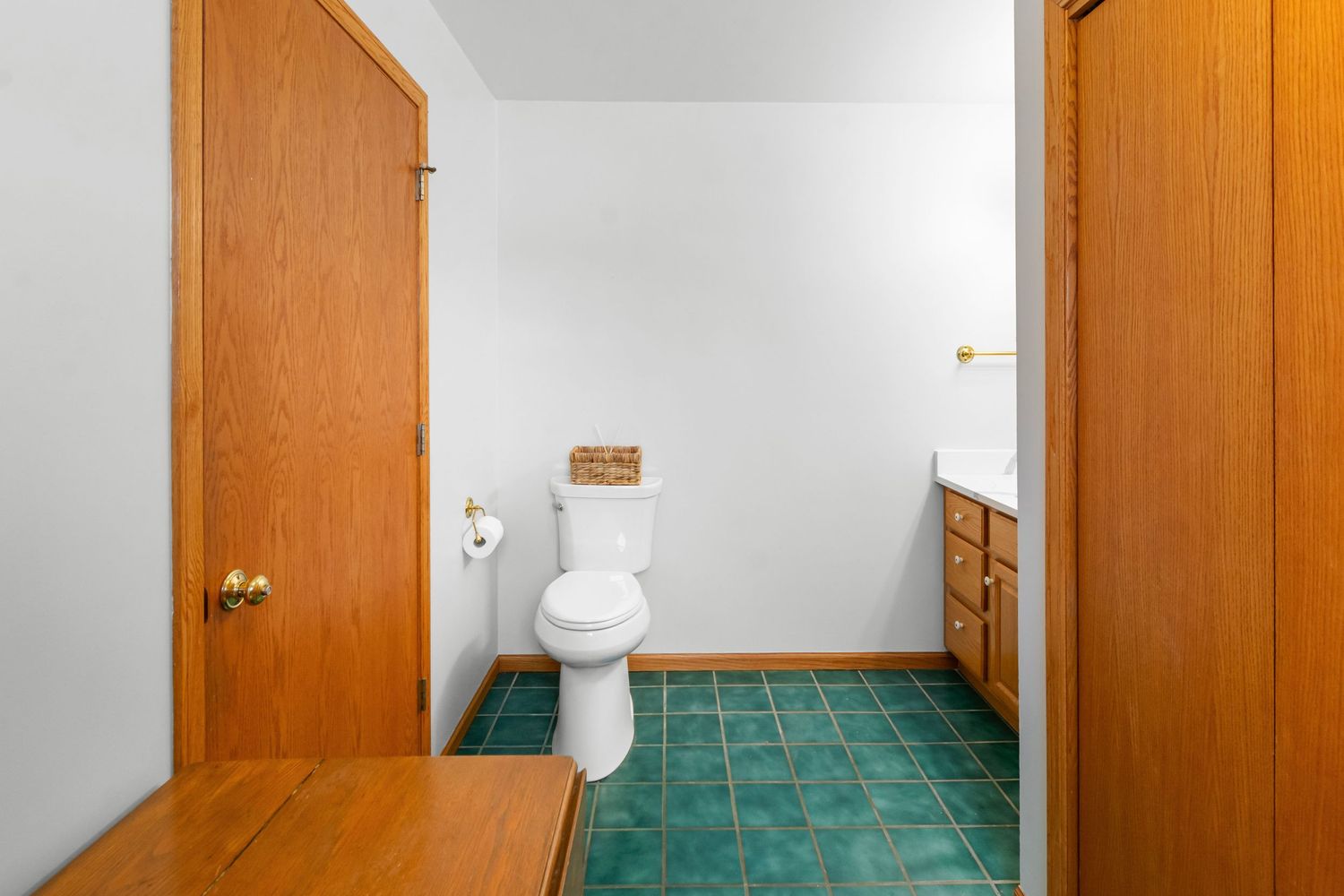 Spacious bathroom featuring green tile flooring and warm wood accents.