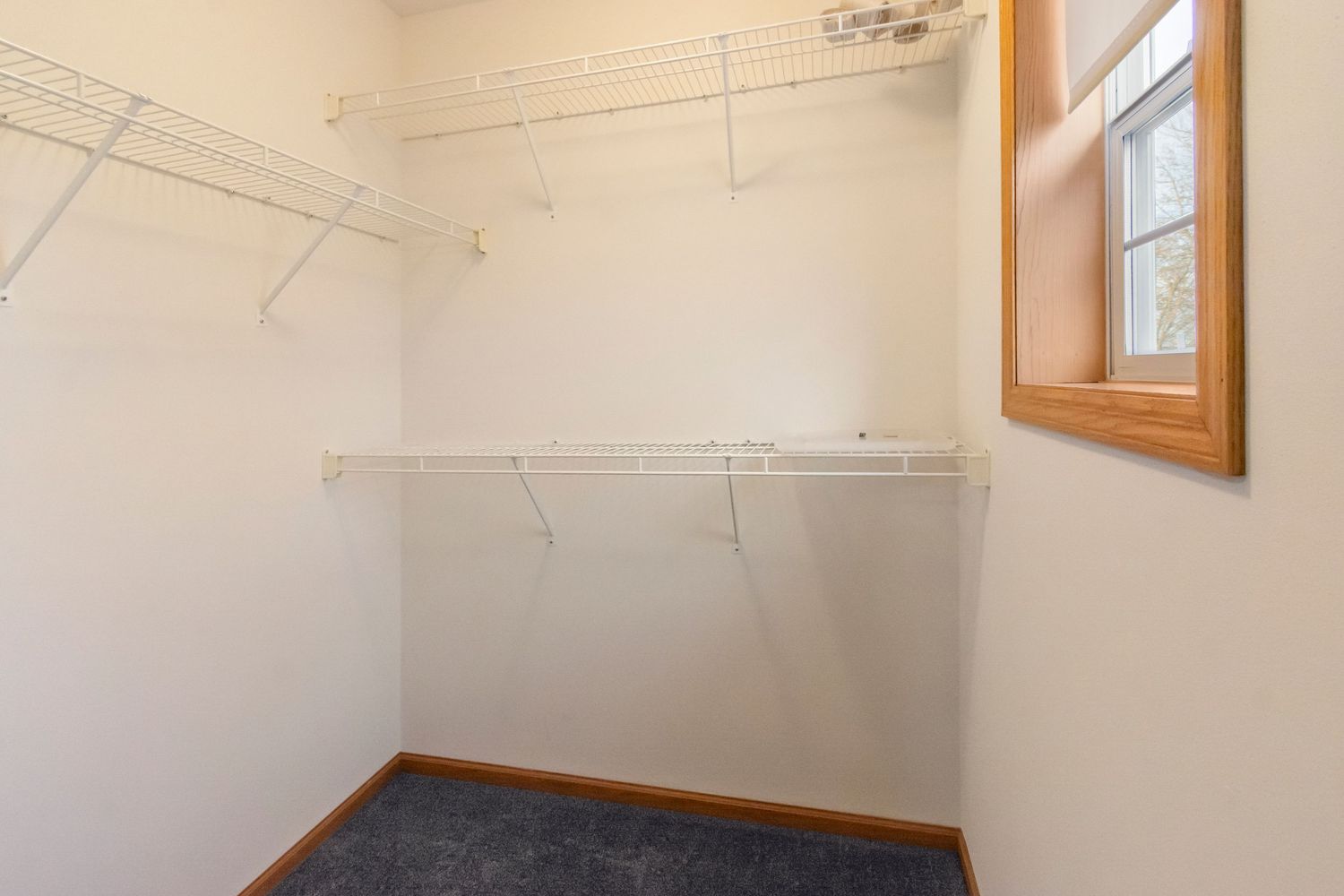 Walk-in closet with wire shelving and small window.