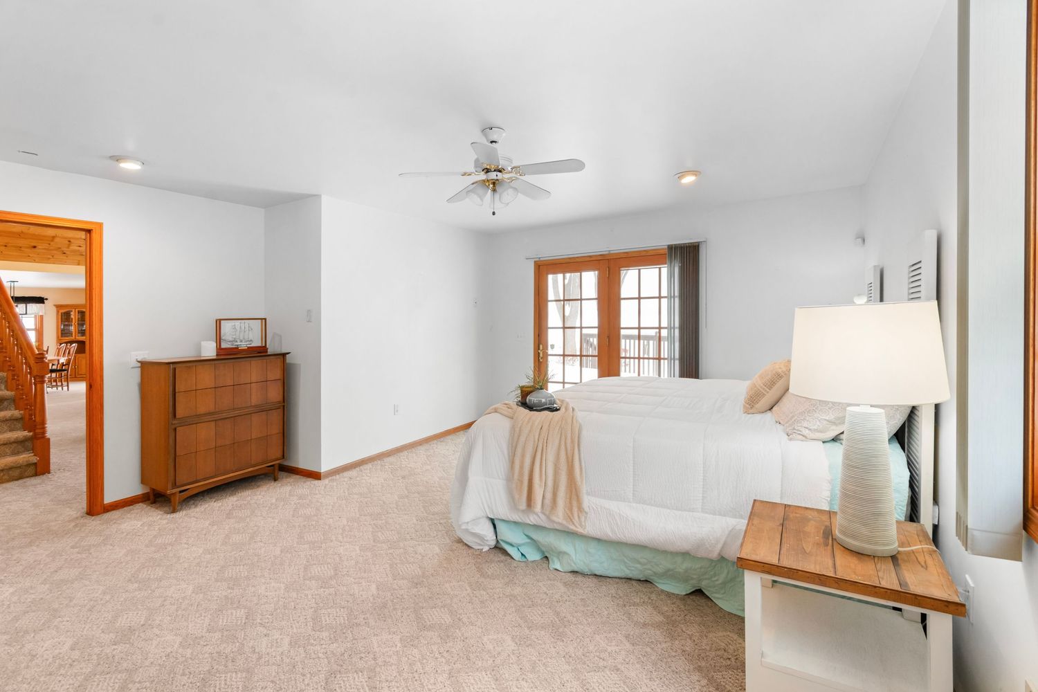 Spacious bedroom with wood trim, carpeted floors, and natural light from French doors.