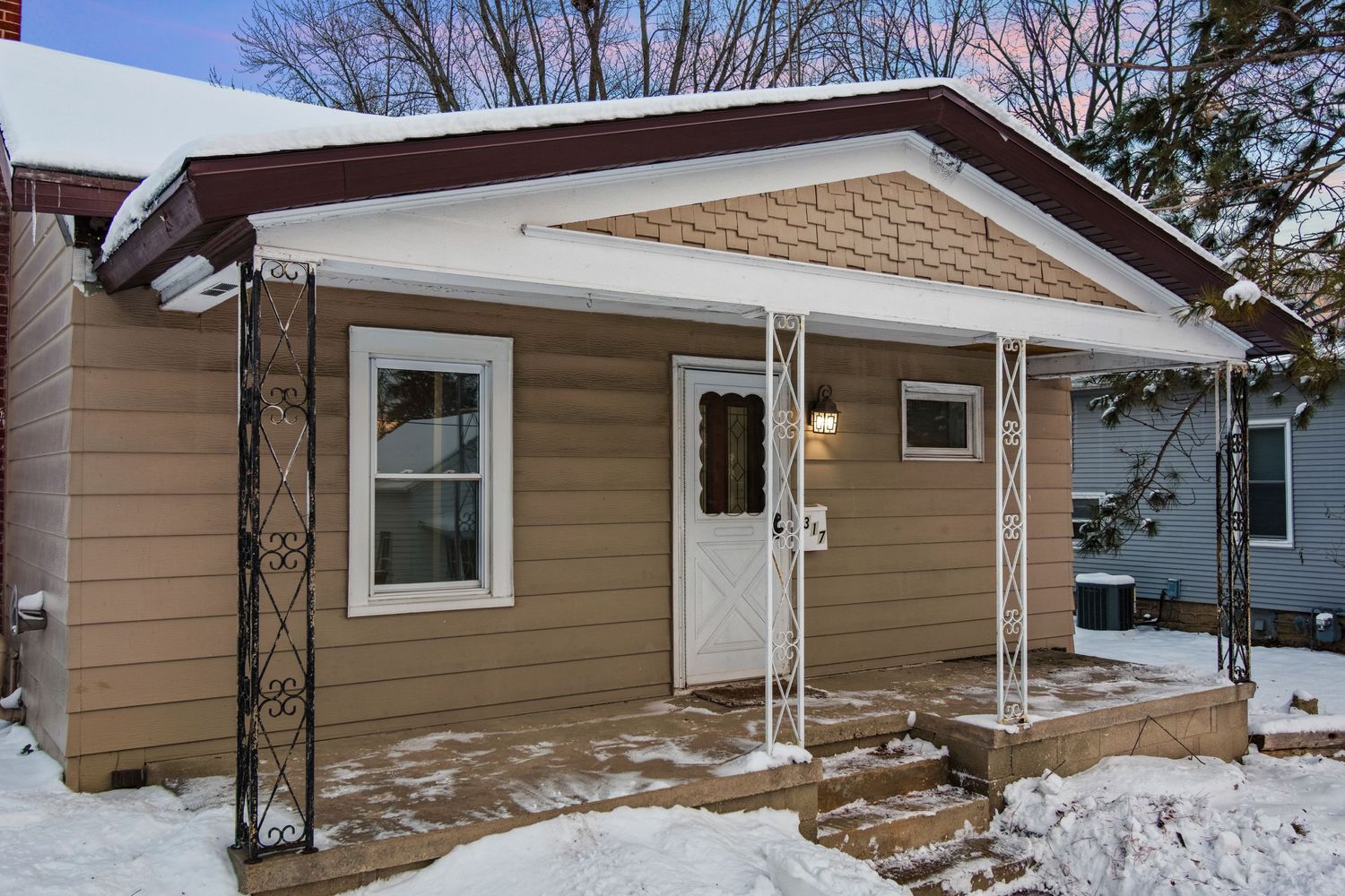 Exterior views of a tan sided ranch style house with snow on the ground from different angles.